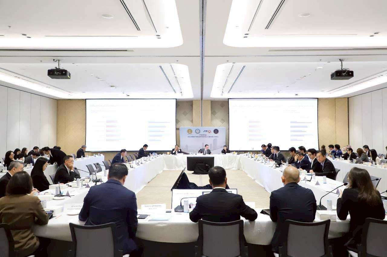 Professionals attend a large conference in a modern meeting room with projection screens.