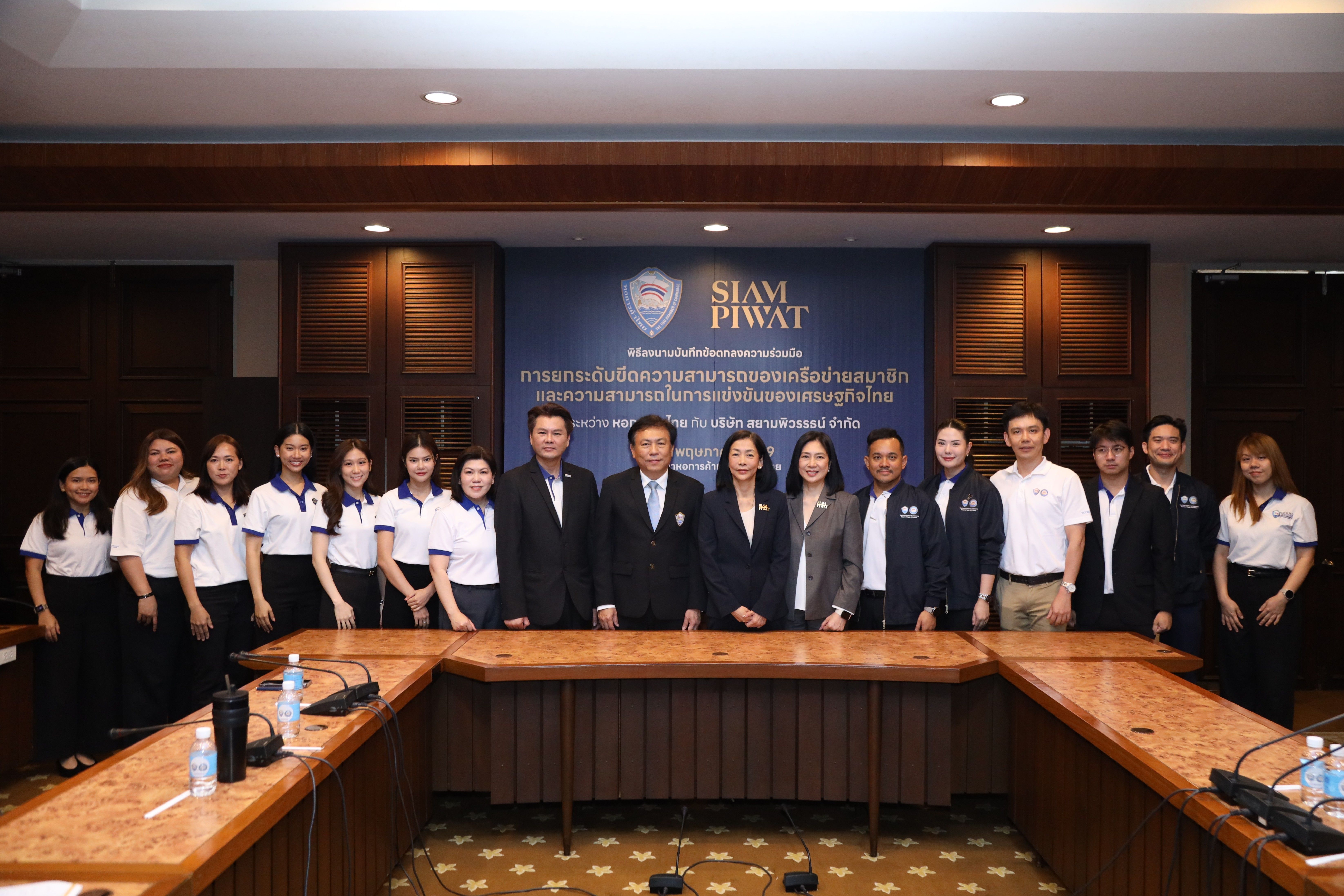 A diverse group of professionals, men and women, pose smiling in a modern conference room.