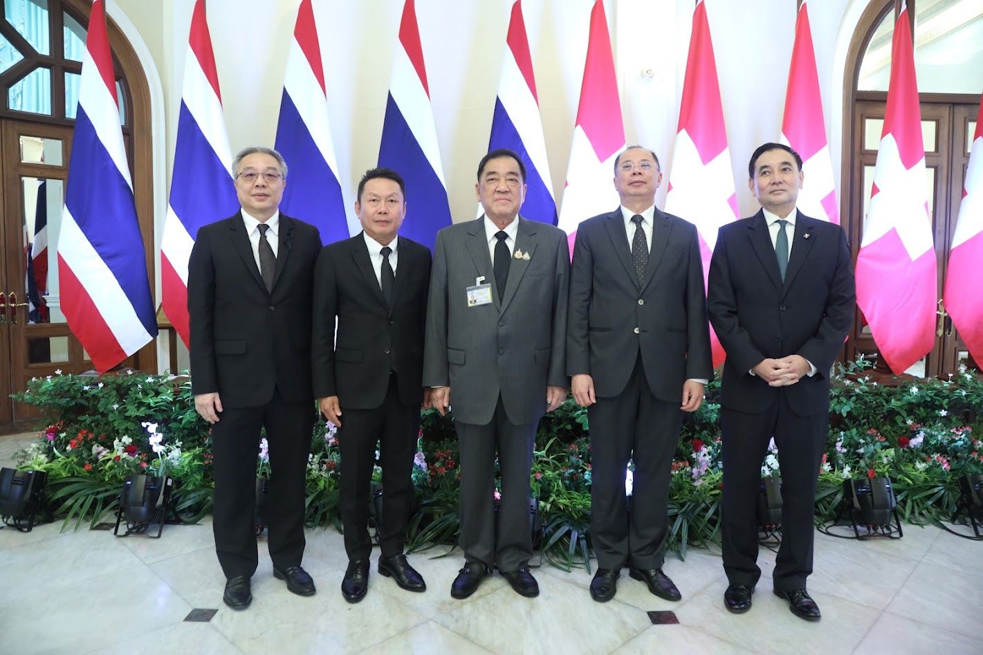 Five officials in suits stand formally before a backdrop of Thai and Canadian flags.