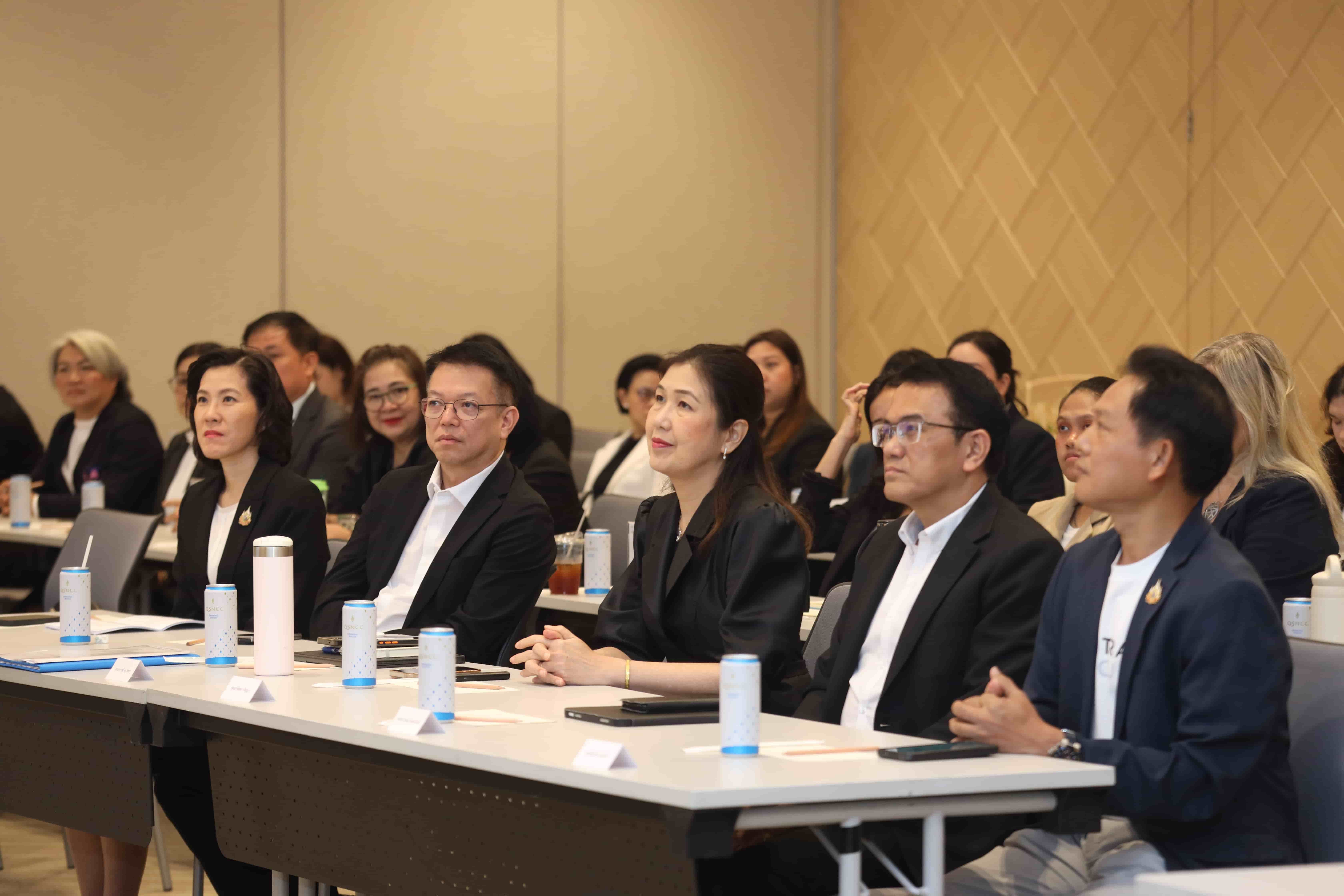 A group of professionals in formal attire attentively listening during a conference session.