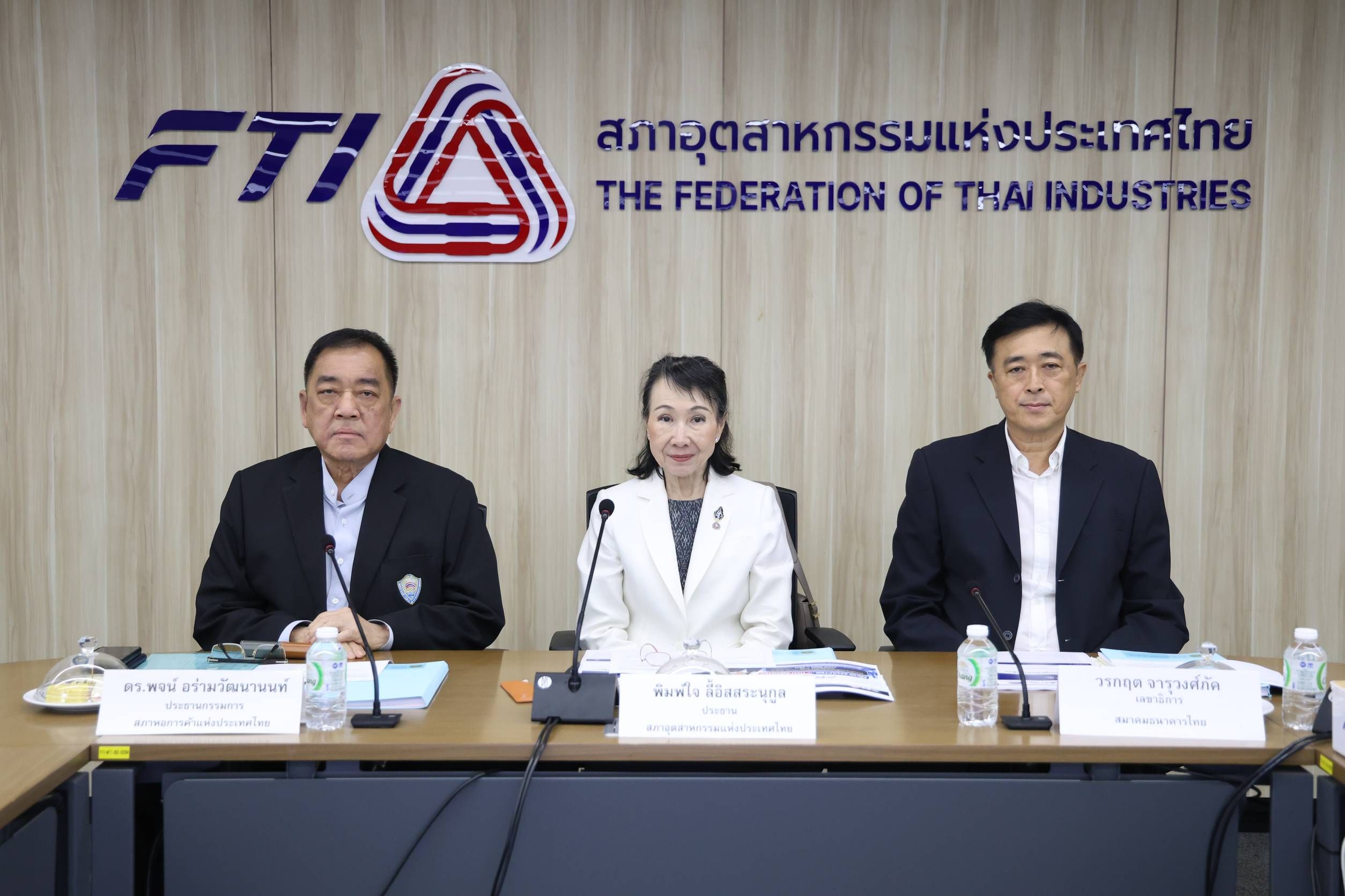 Three people, two men and one woman, sit at a table with the FTI logo.