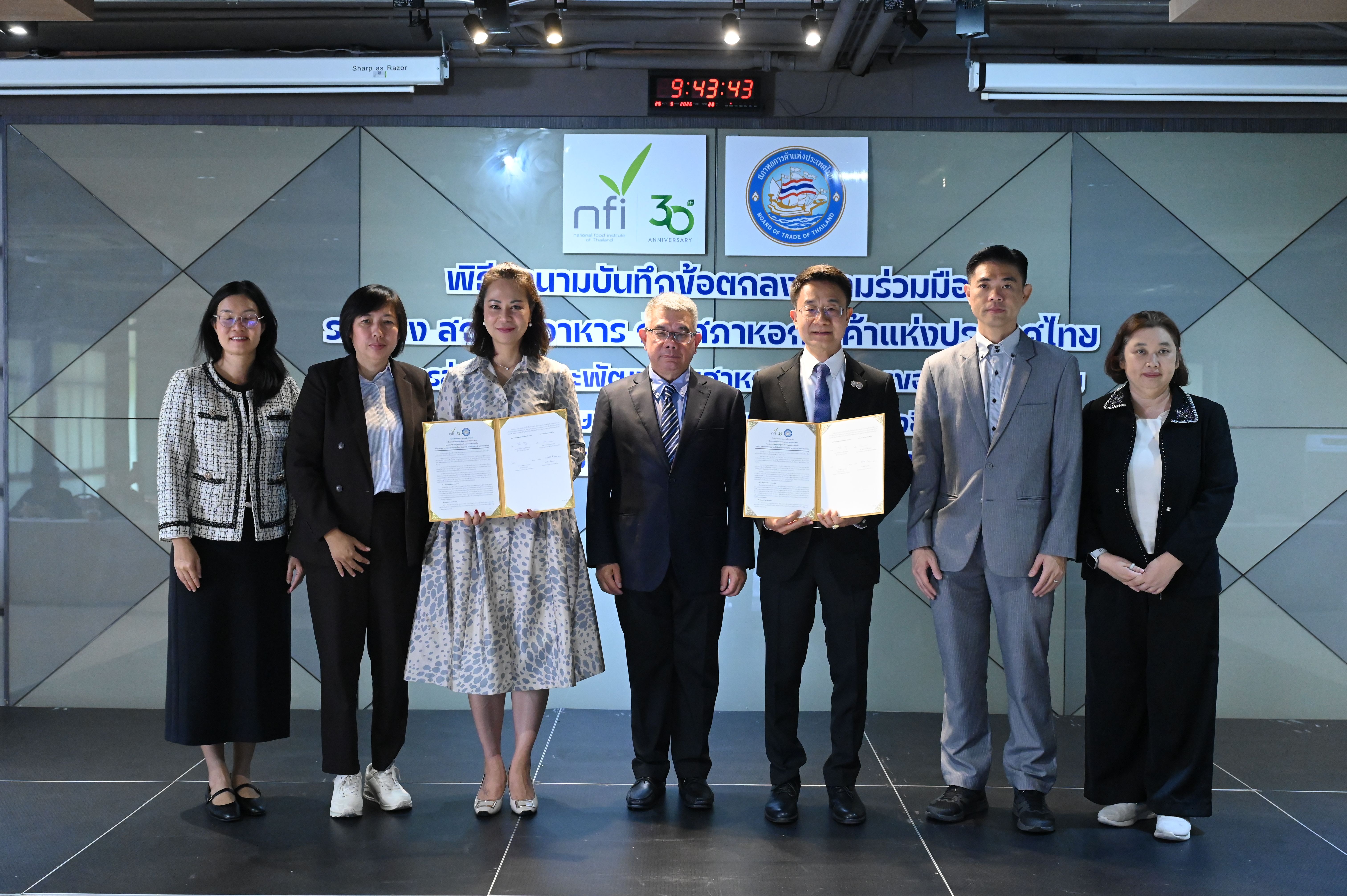 Seven professionals in business attire stand holding documents at a formal event.