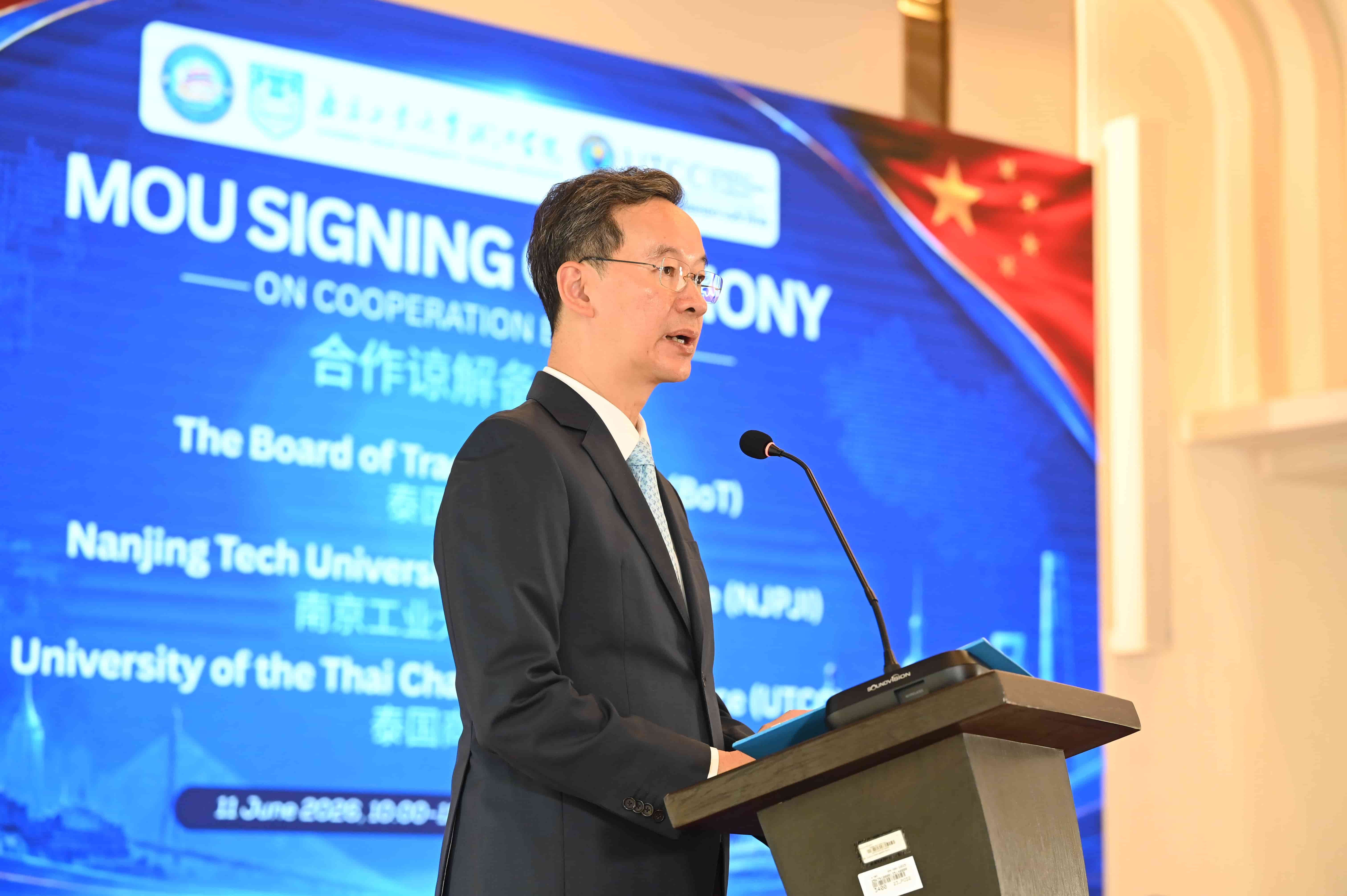 A man in a dark suit speaks at a podium during an MOU signing ceremony on cooperation.