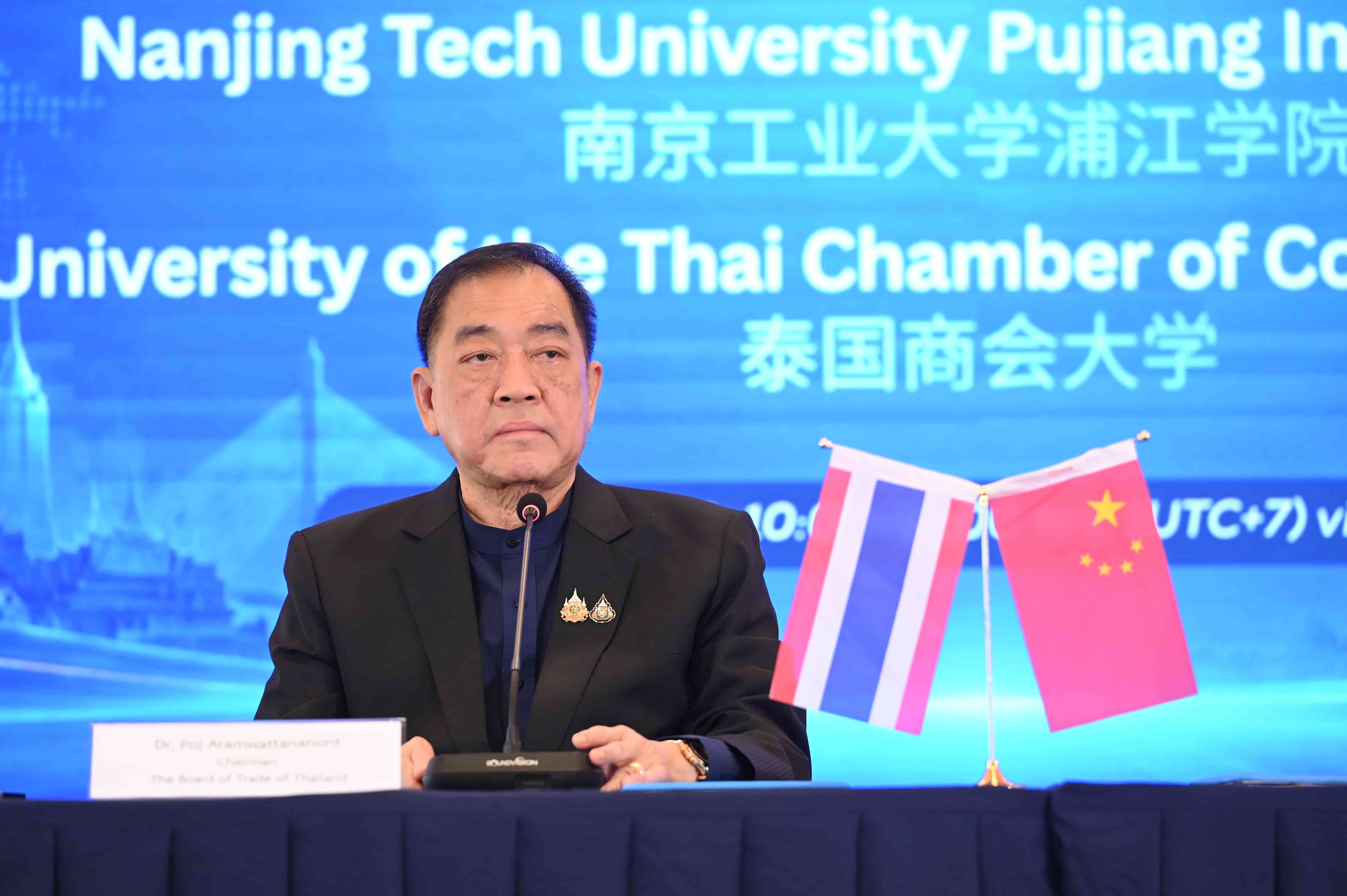 Speaker at an international university event, featuring banners and Thai and Chinese national flags.