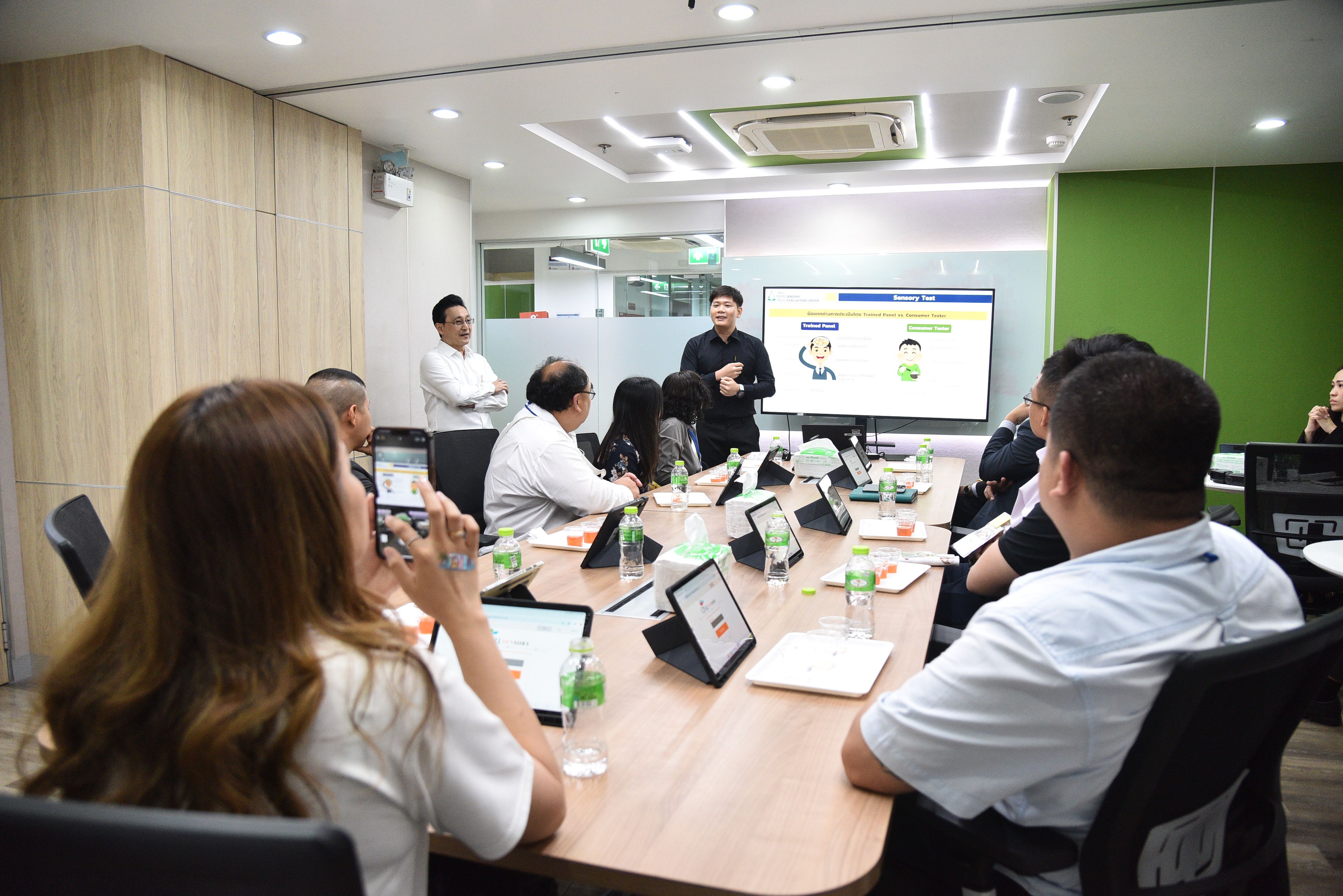 Presenter leads a meeting in a modern conference room with screen visuals.