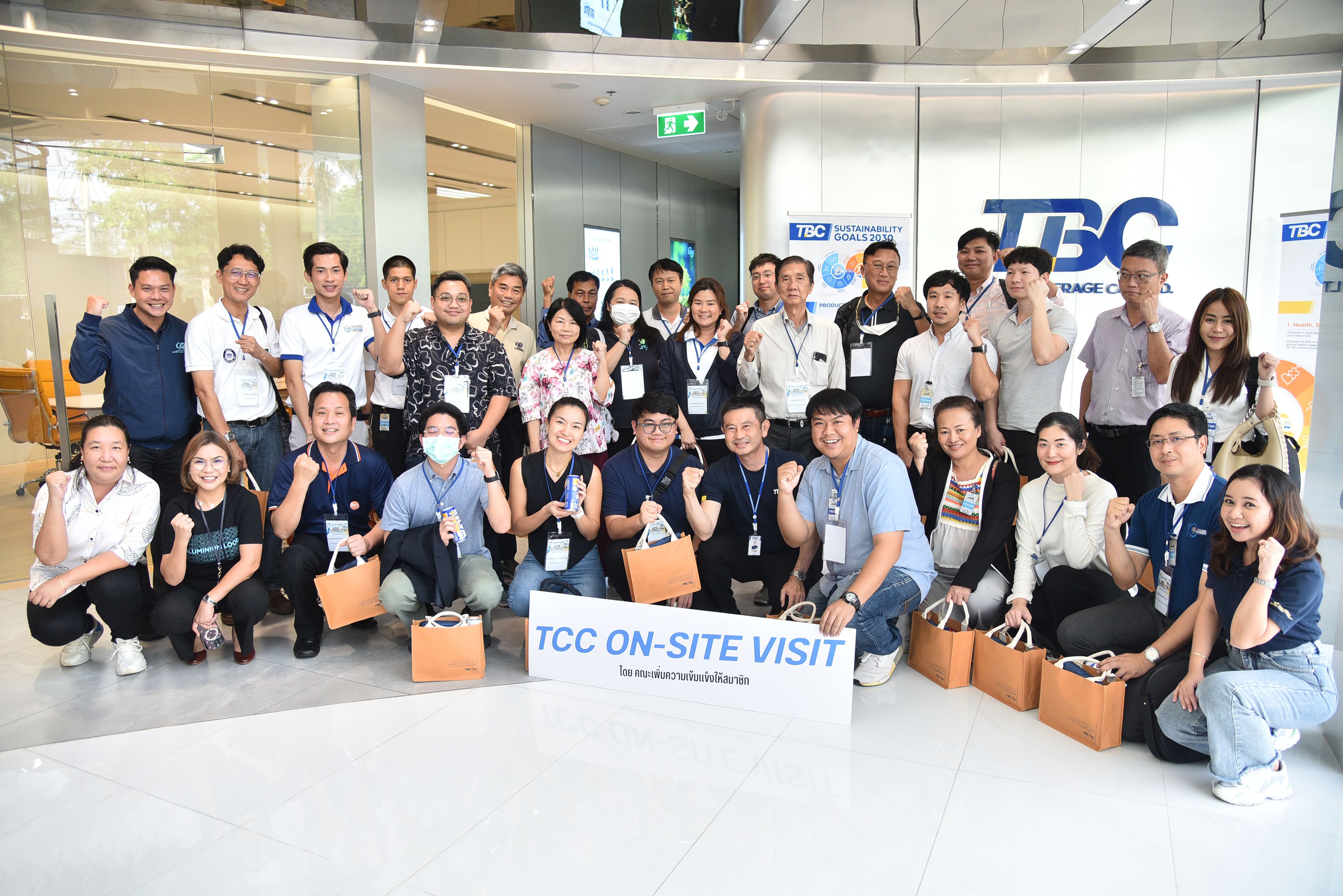 A large group of diverse professionals smiling and posing during a TCC on-site visit.