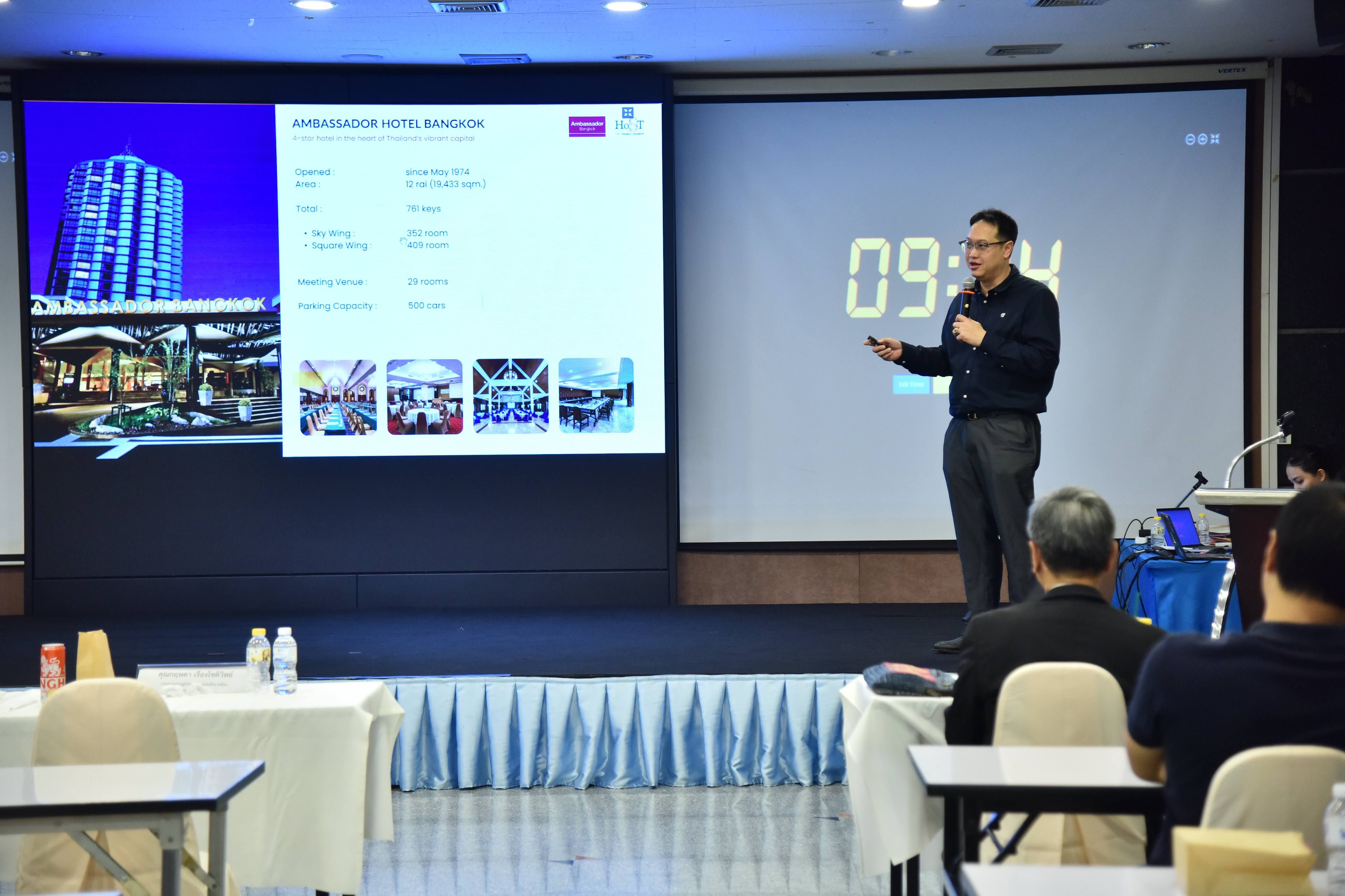 A man presents slides and a digital timer on a large screen to an audience.