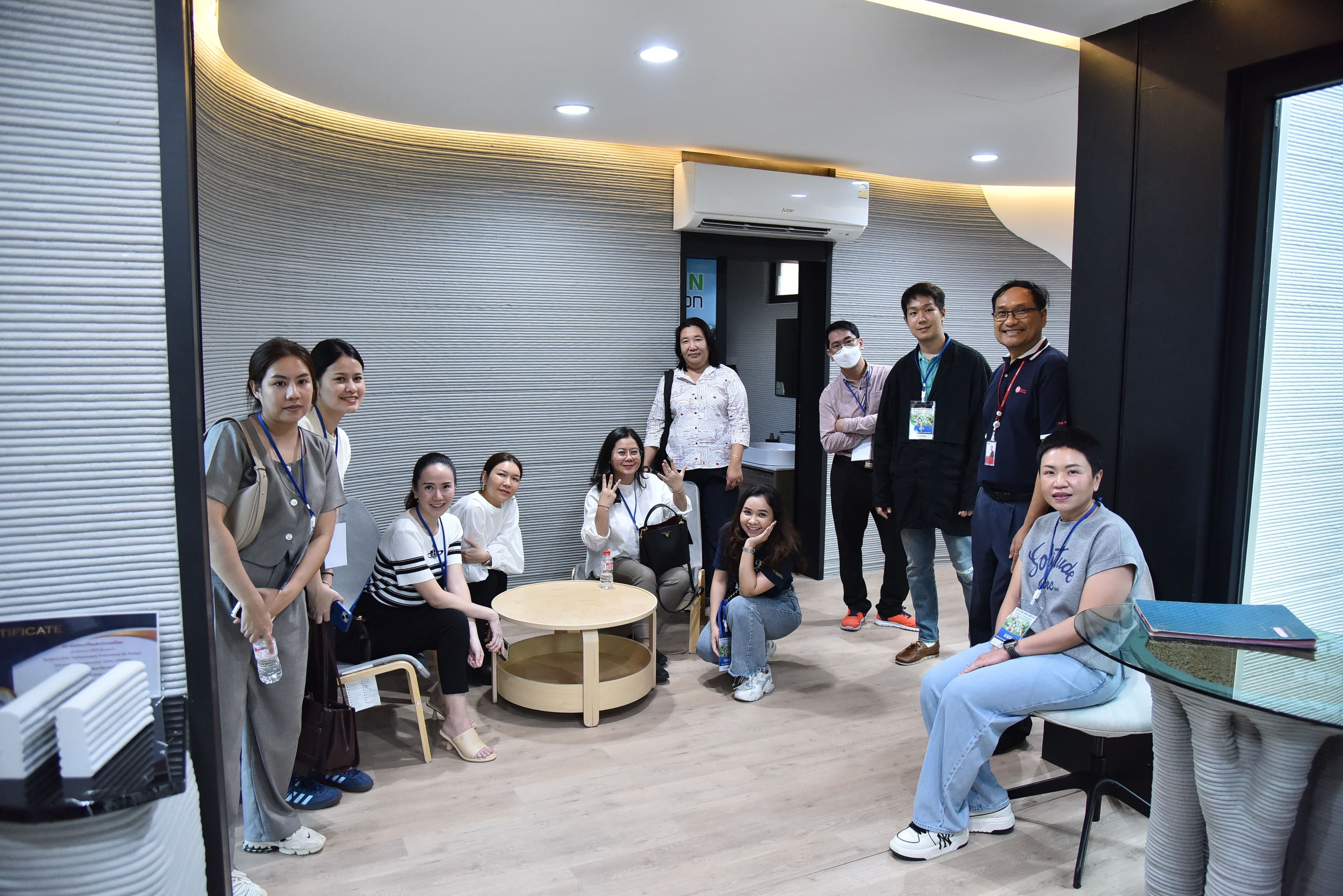 A group of people gathering in a modern room with curved, textured walls.