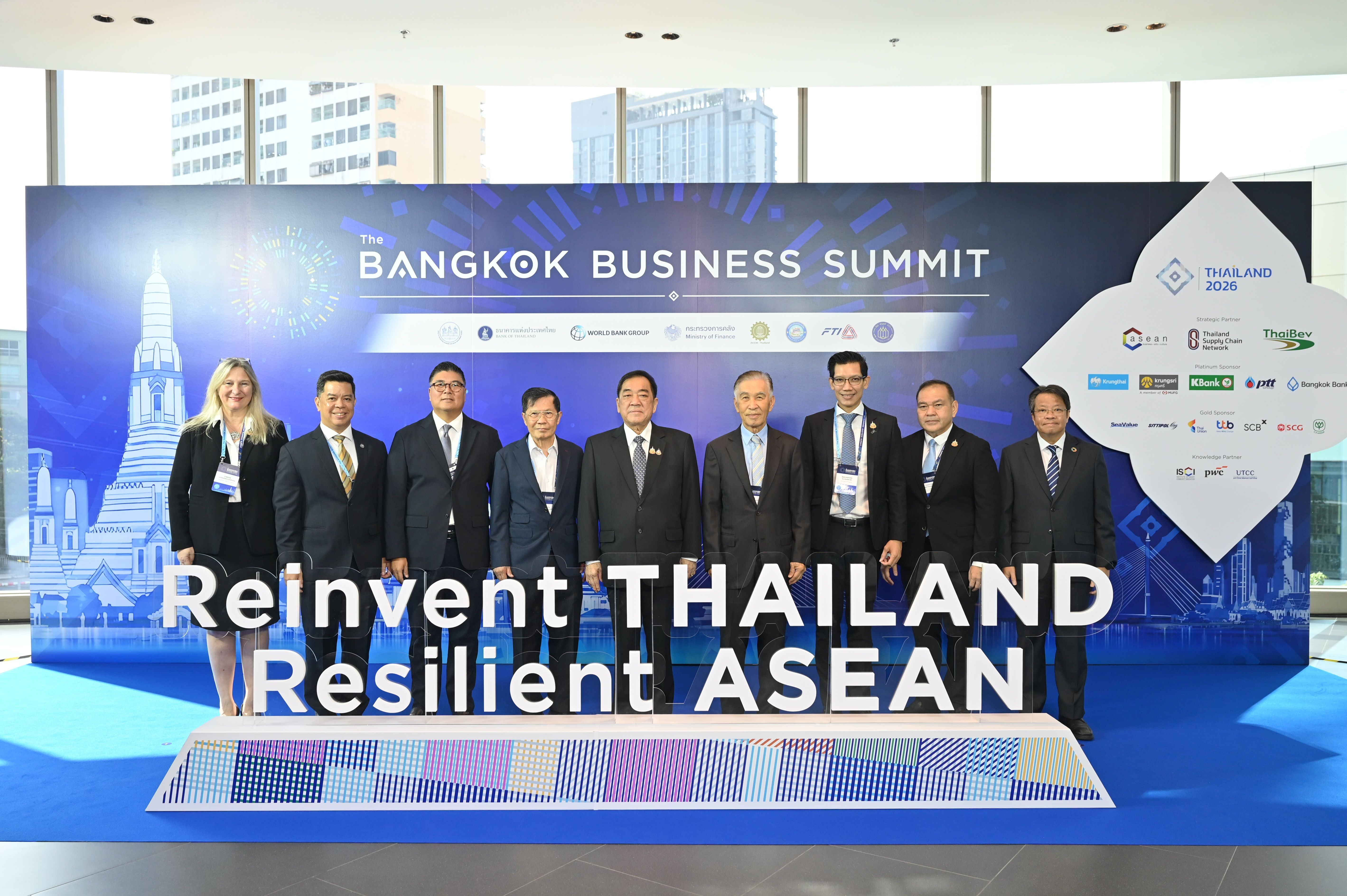 Business leaders pose at Bangkok Business Summit event with 'Reinvent THAILAND Resilient ASEAN' sign.