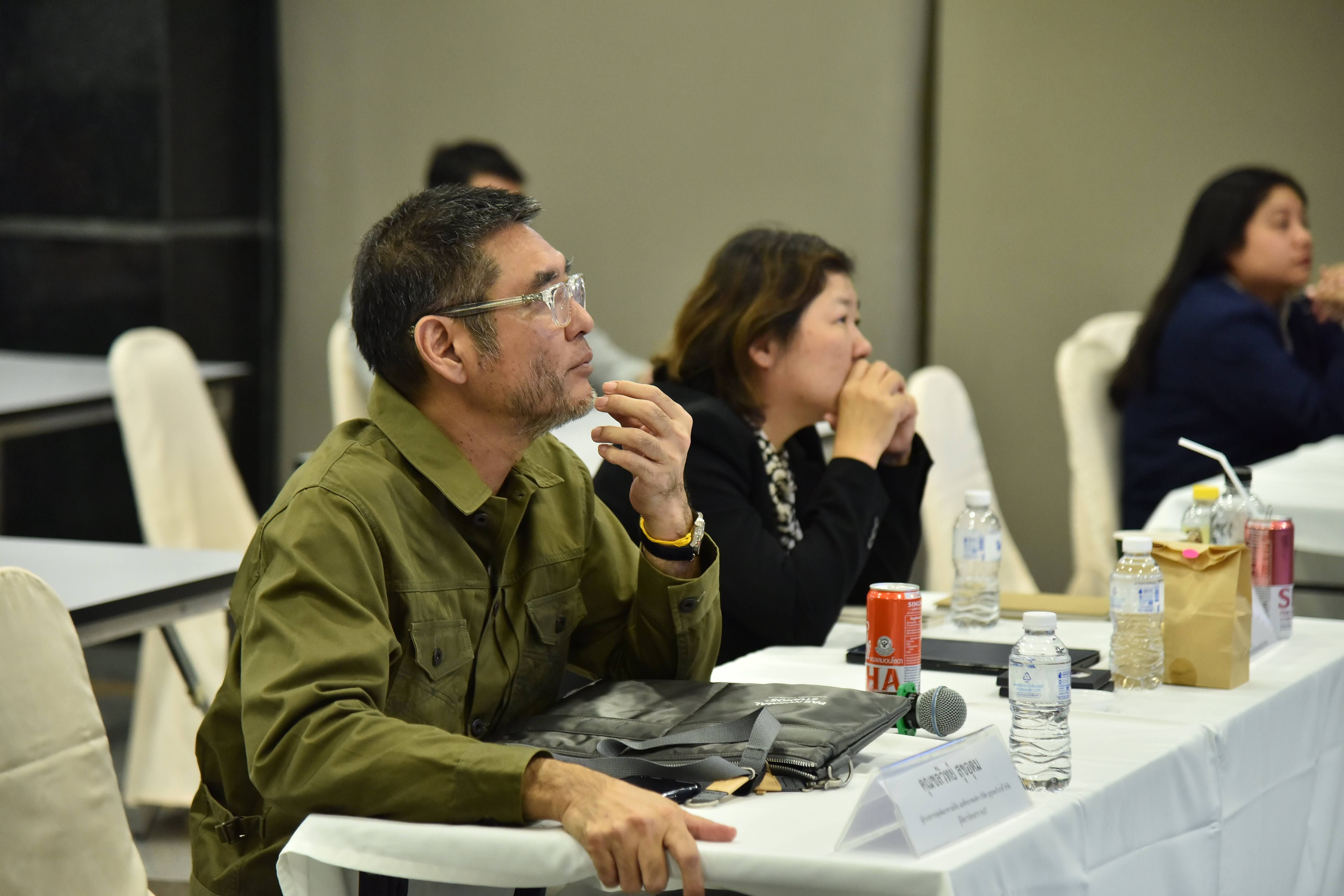 Man in green shirt and woman attentively listening at a professional conference table.