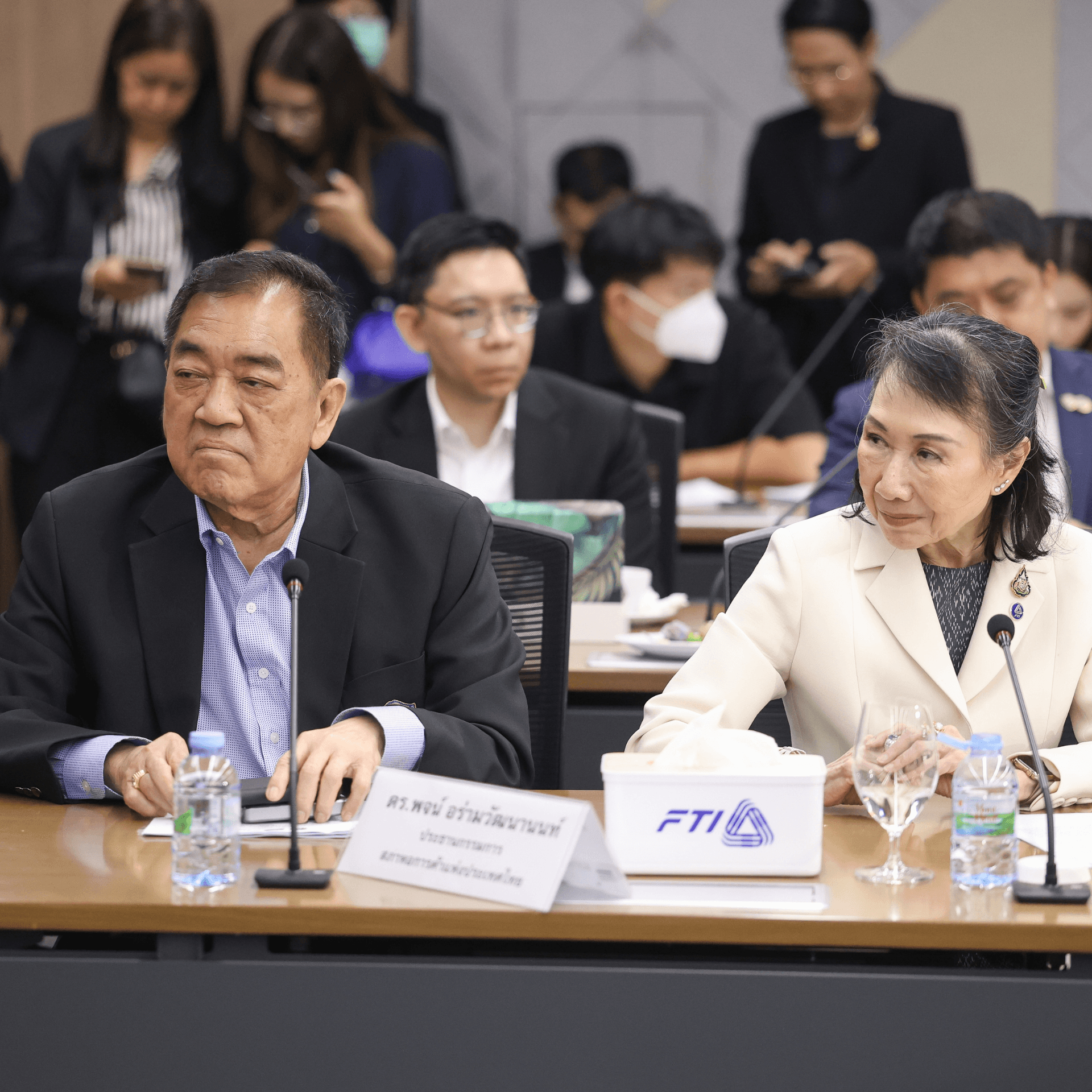 Elderly man and woman attending a formal meeting at a conference table.