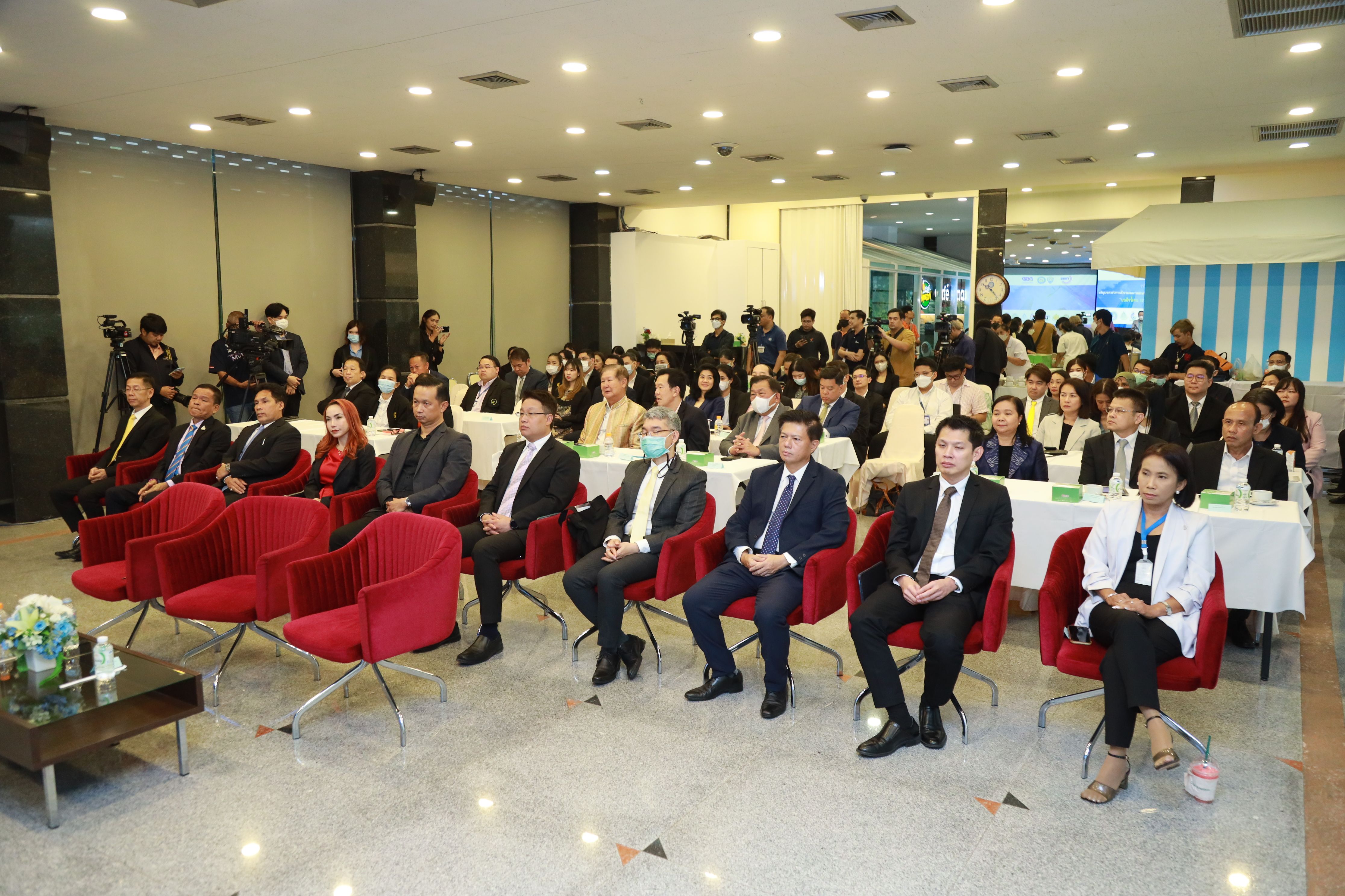 Audience in business attire attending a conference or presentation in a well-lit room.