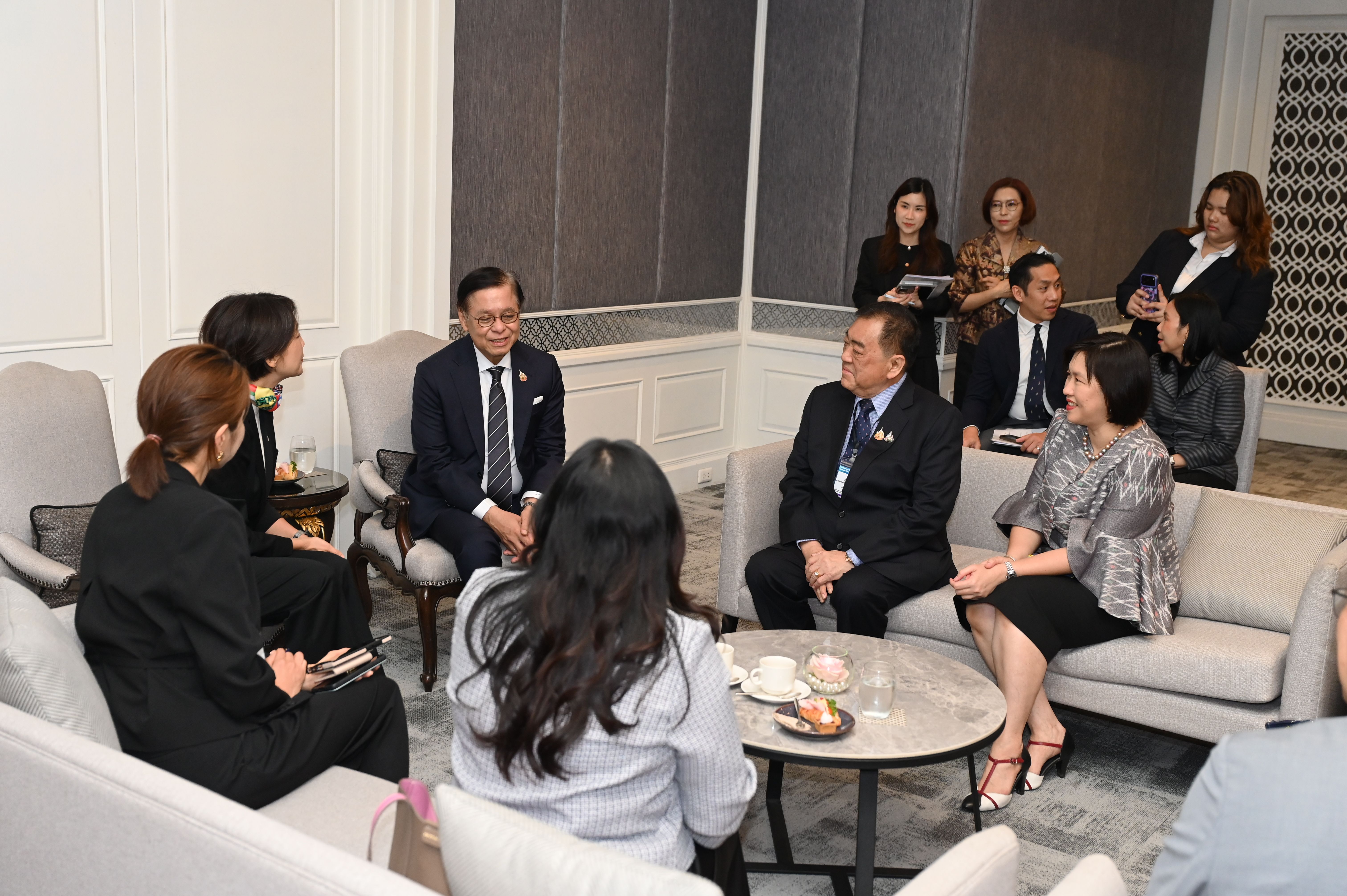 Group of East Asian professionals meeting in a modern, well-appointed room.