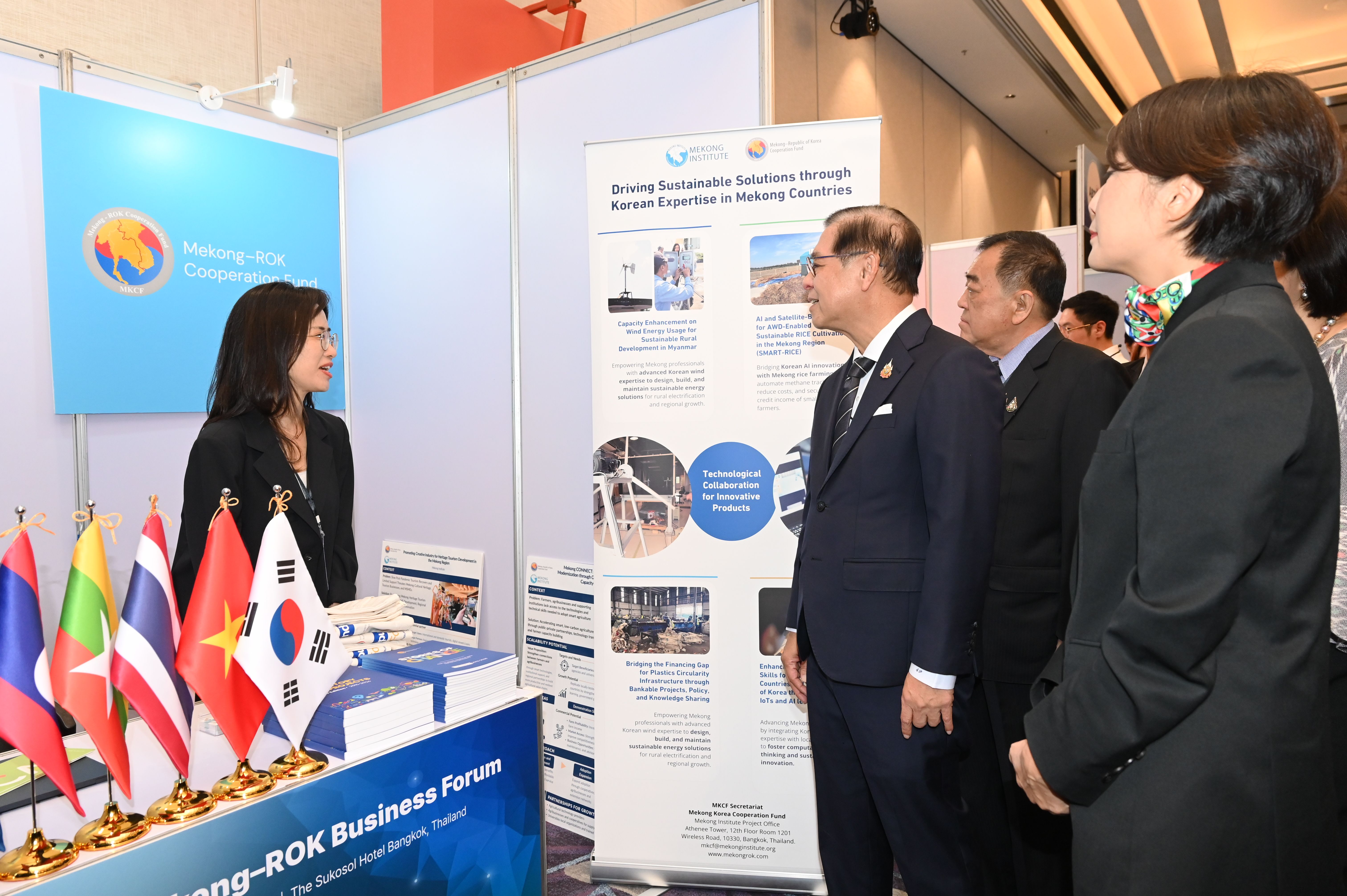 Delegates discuss at an international business forum booth featuring country flags.