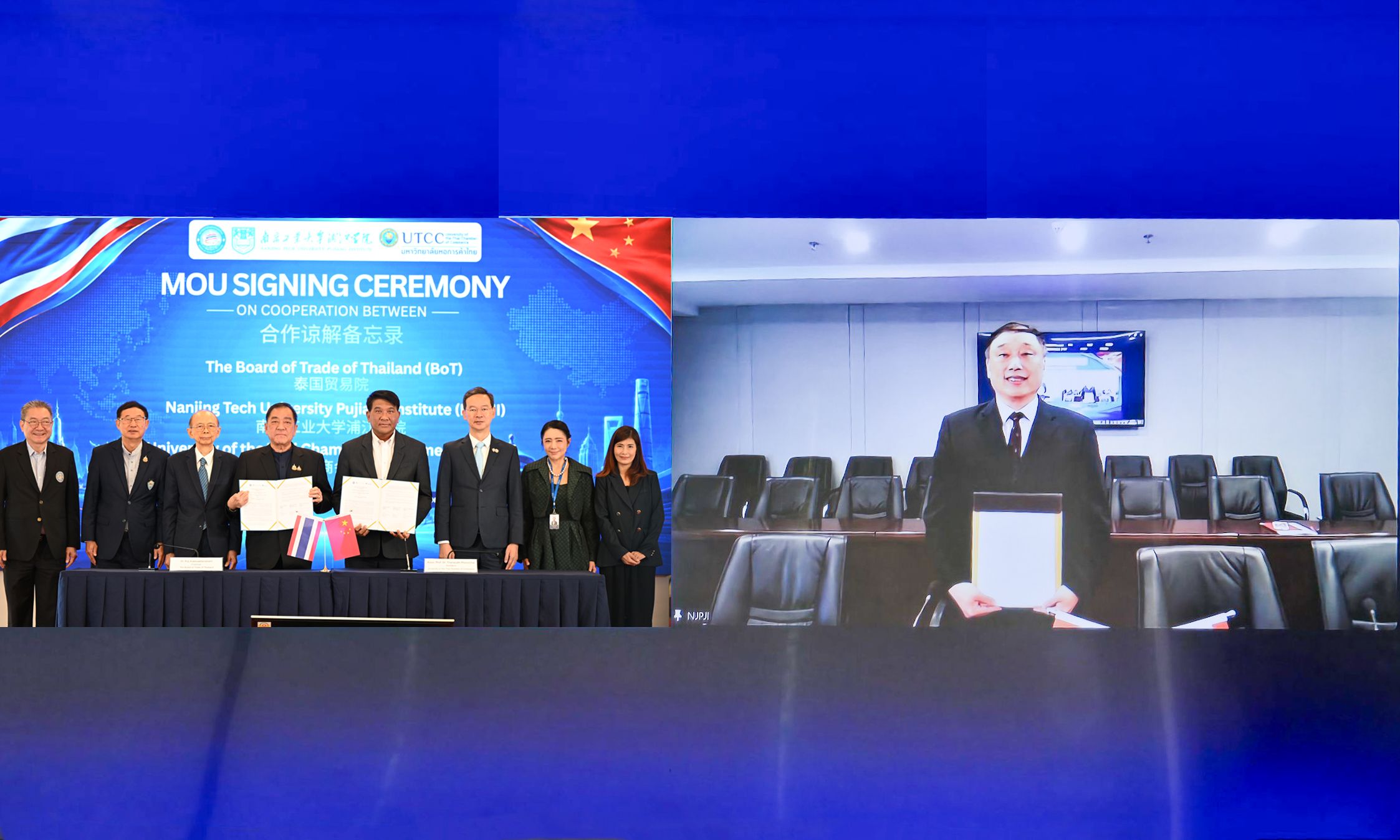 Group of people signing documents during an MOU ceremony, with one participant joining virtually.