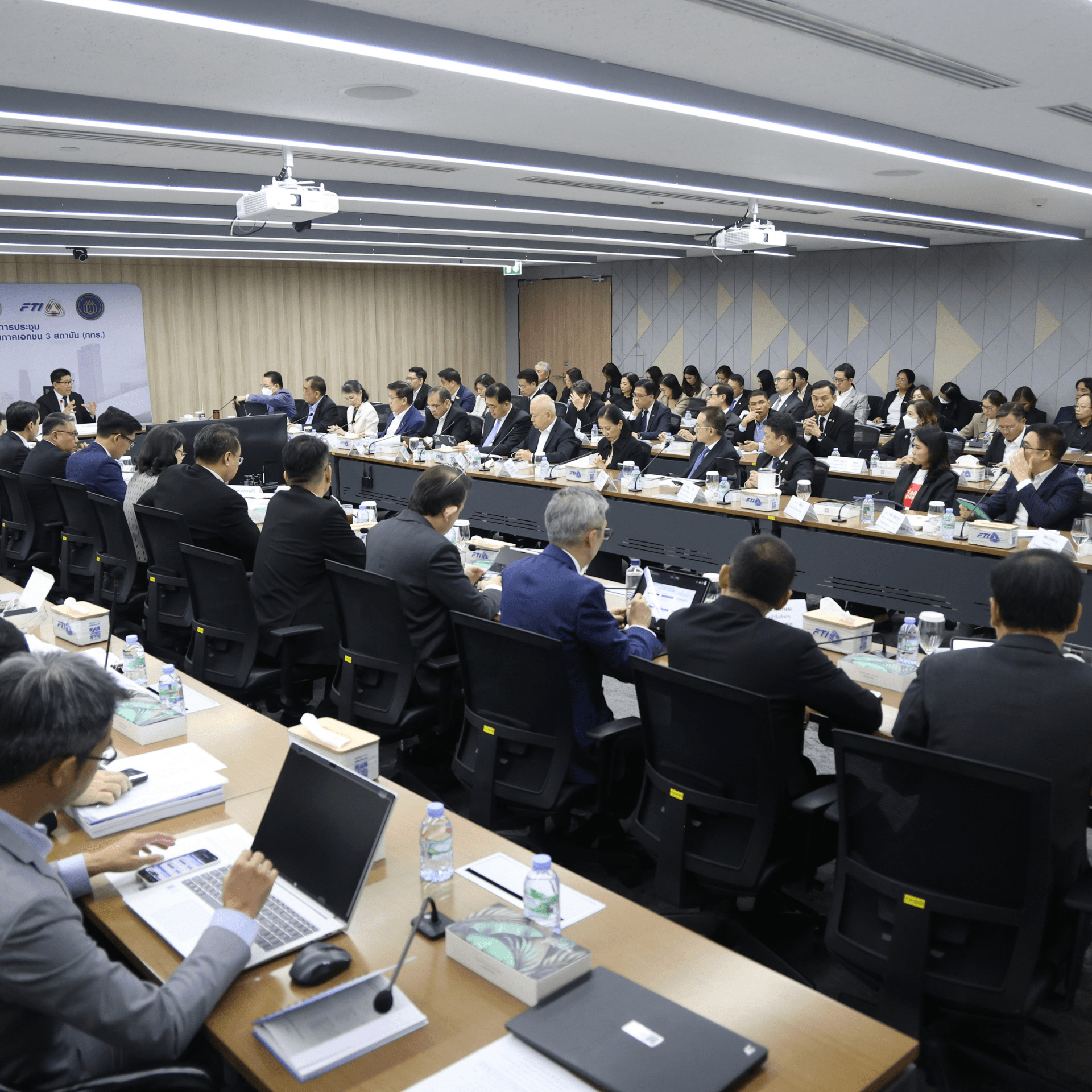 Attendees gather for a formal business meeting in a modern conference room.