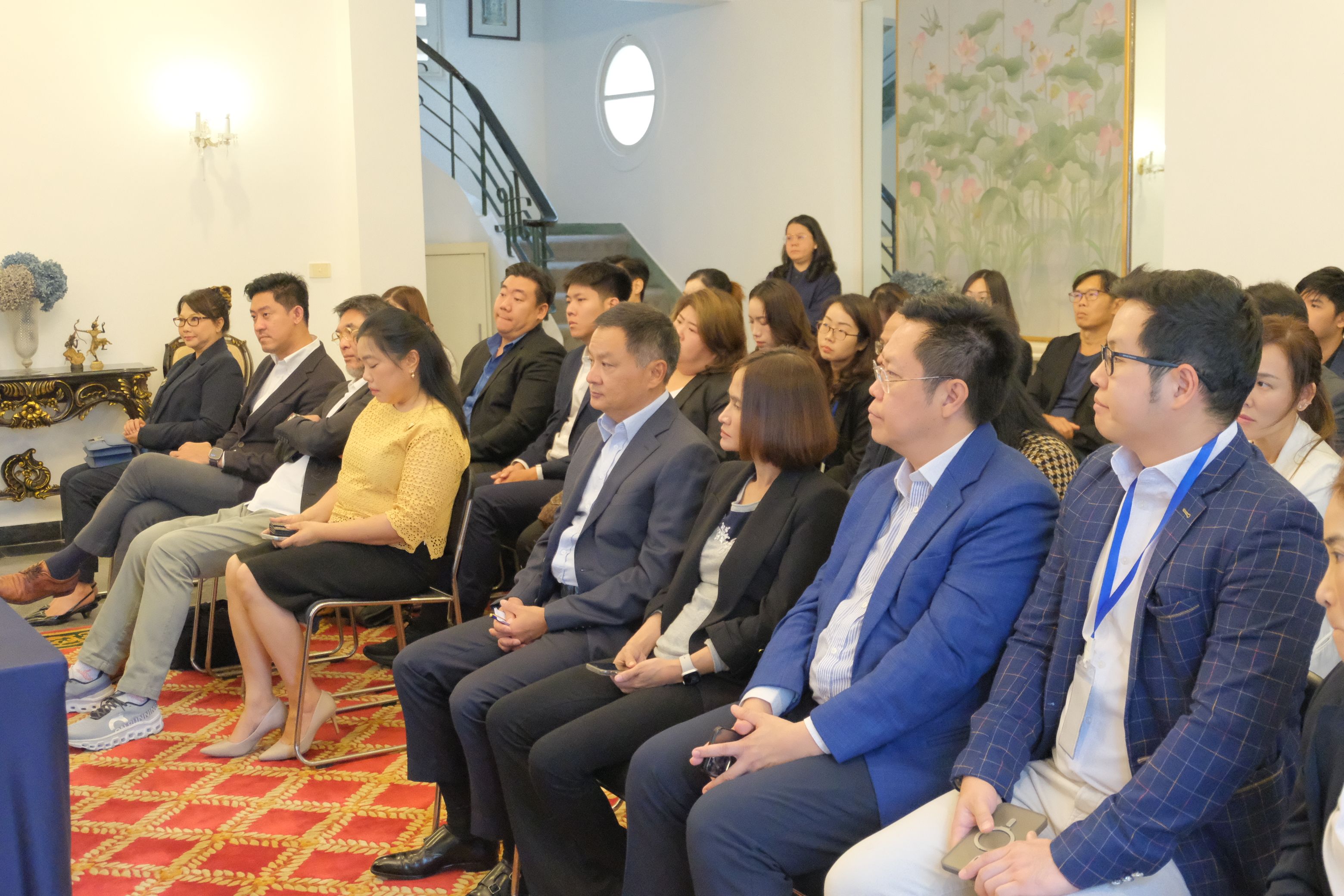 A diverse group of professionals seated, attentively listening during a corporate event.