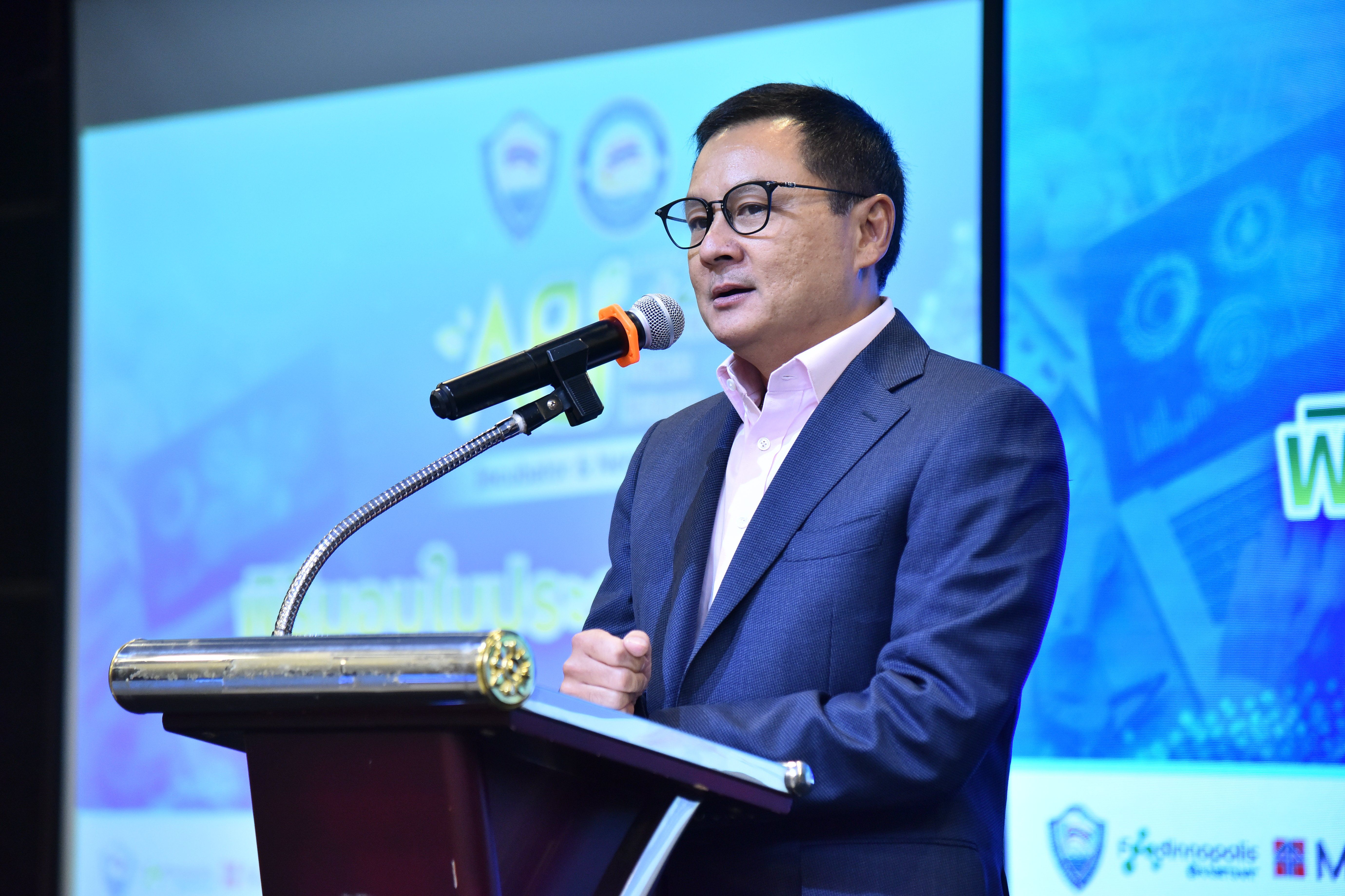 Man in glasses speaking at a podium with a microphone during a presentation.