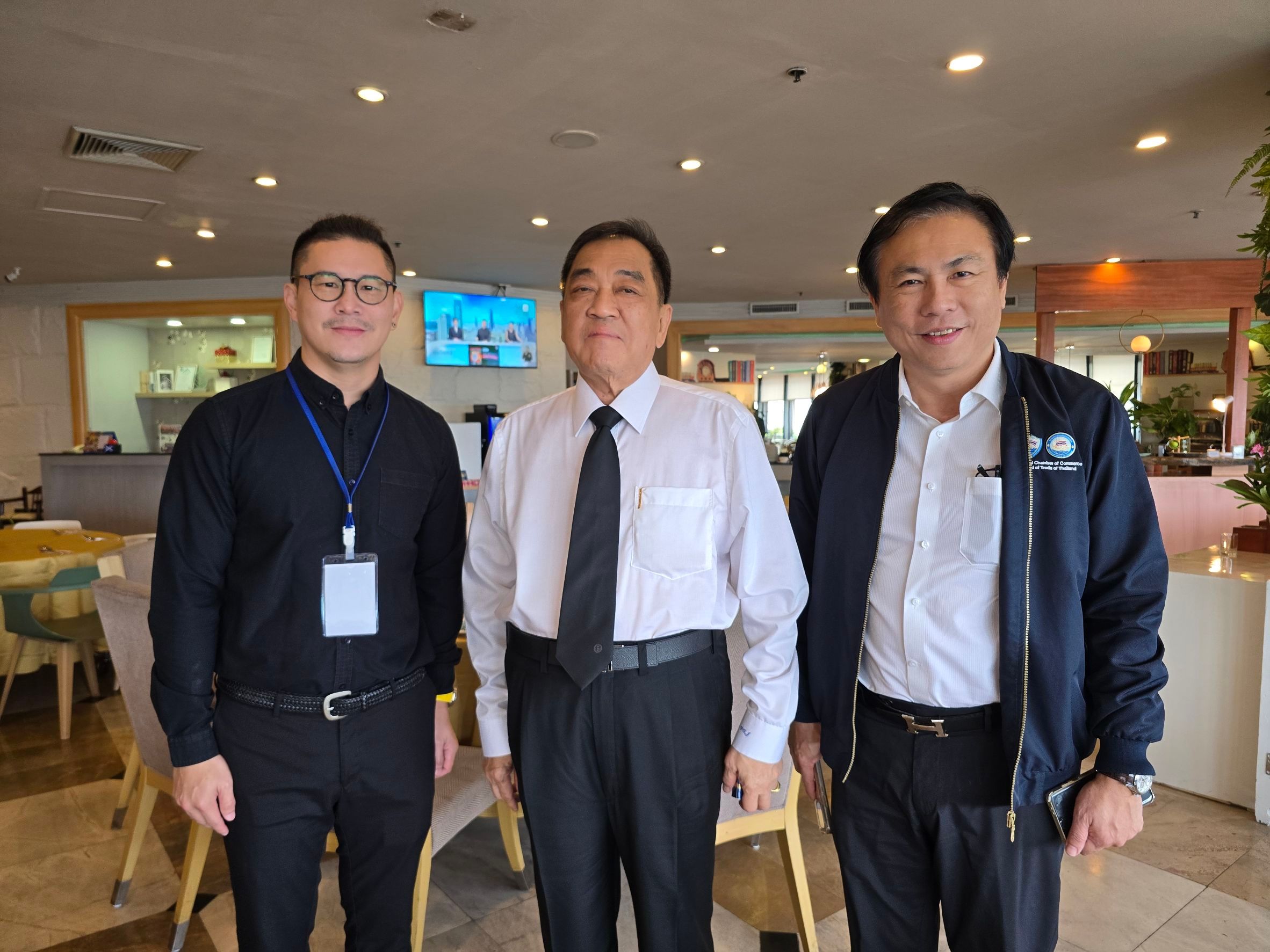 Three professional men stand together, smiling, in a brightly lit indoor setting.