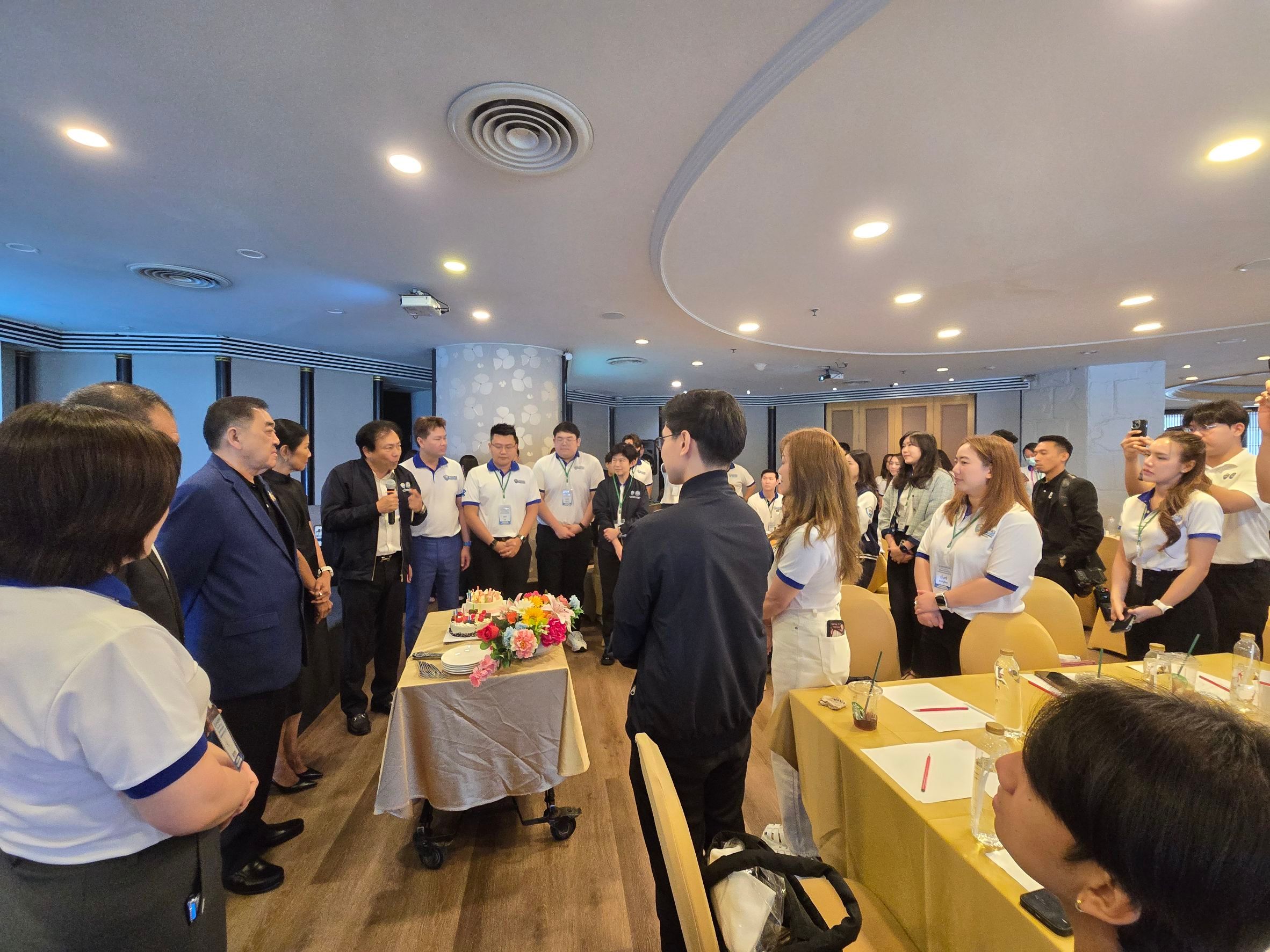 Group of students and adults gathered in a brightly lit indoor event room.