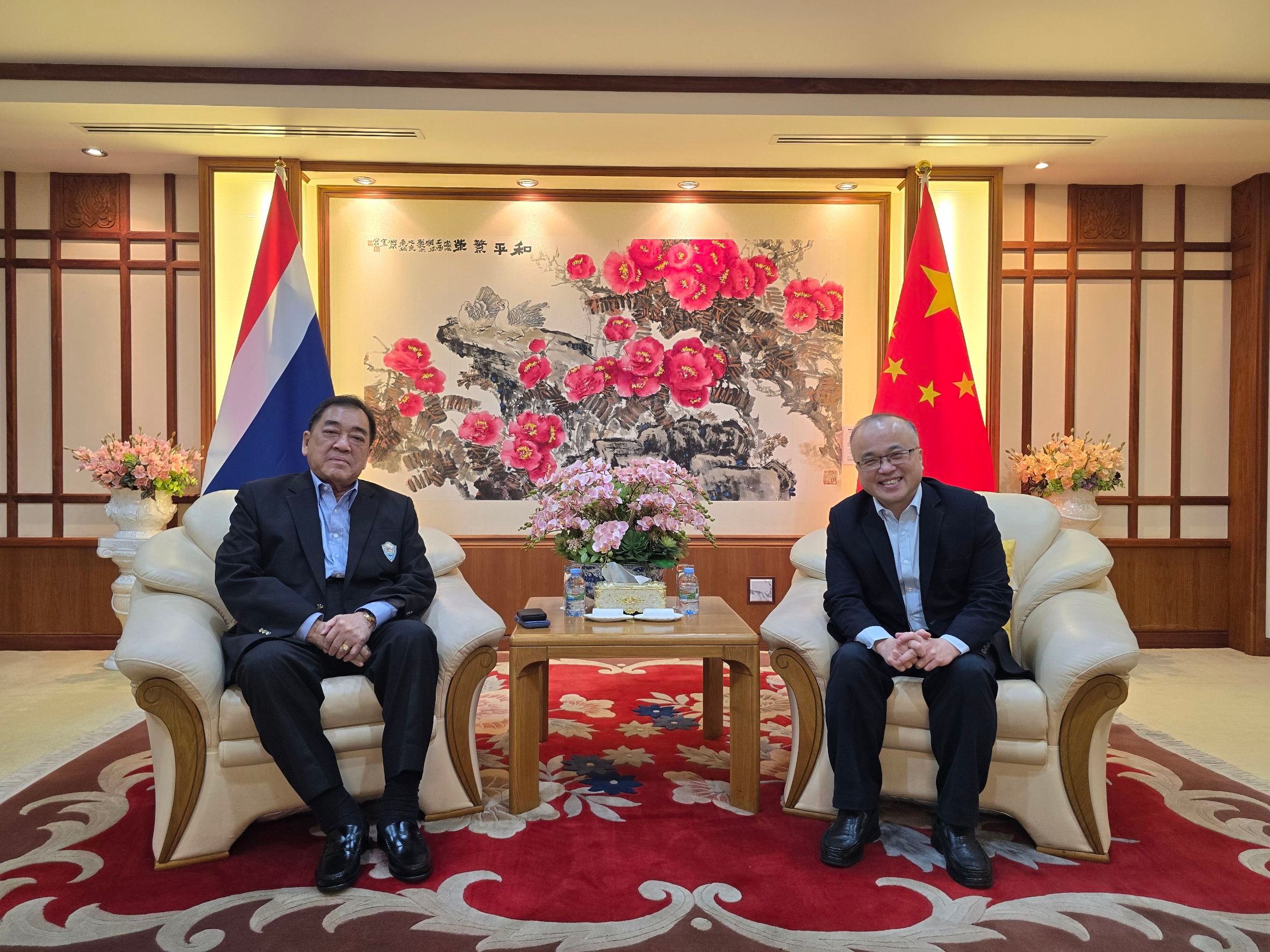 Two diplomats, one from Thailand and one from China, meet in an office.
