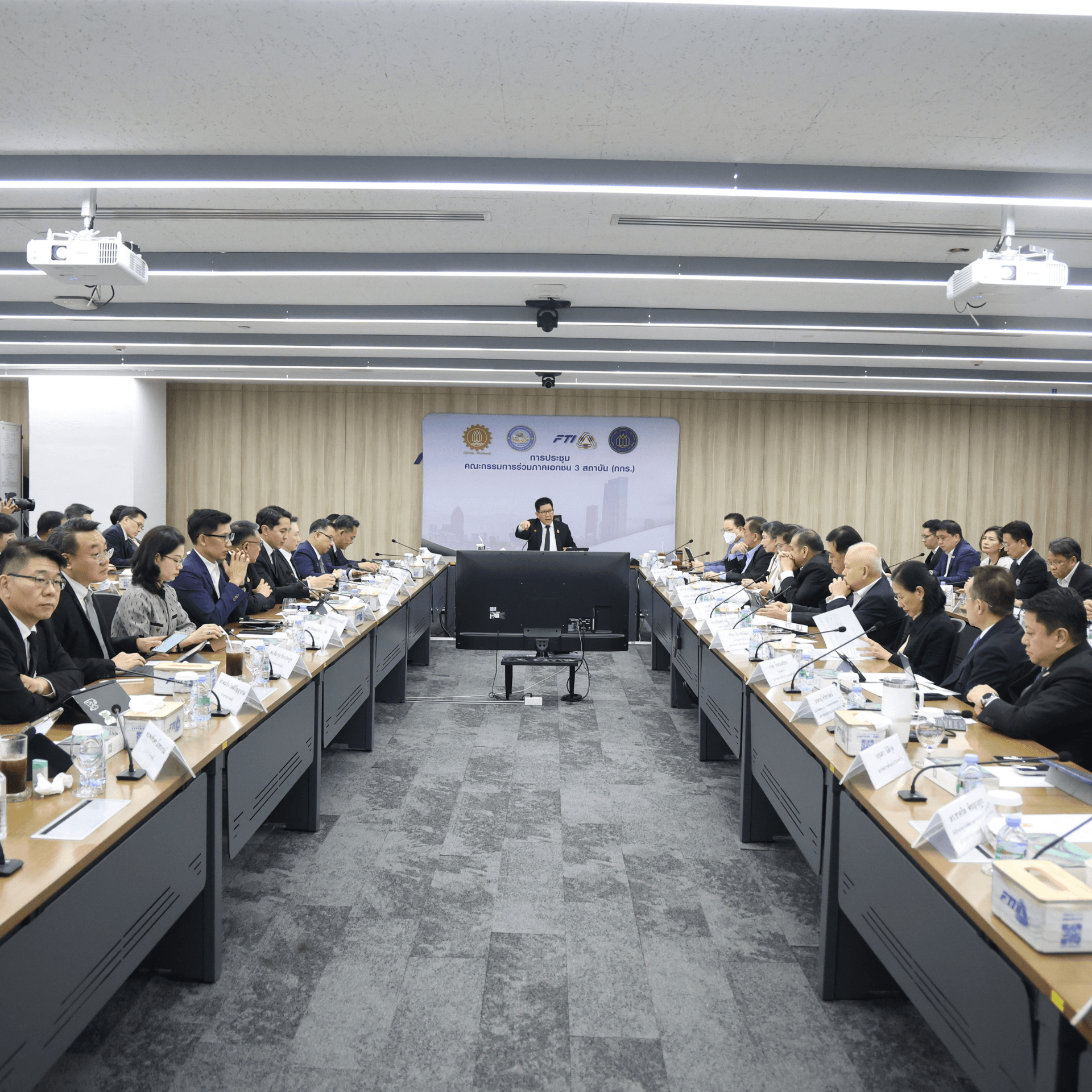 Professionals attend a corporate meeting in a modern conference room with a speaker.