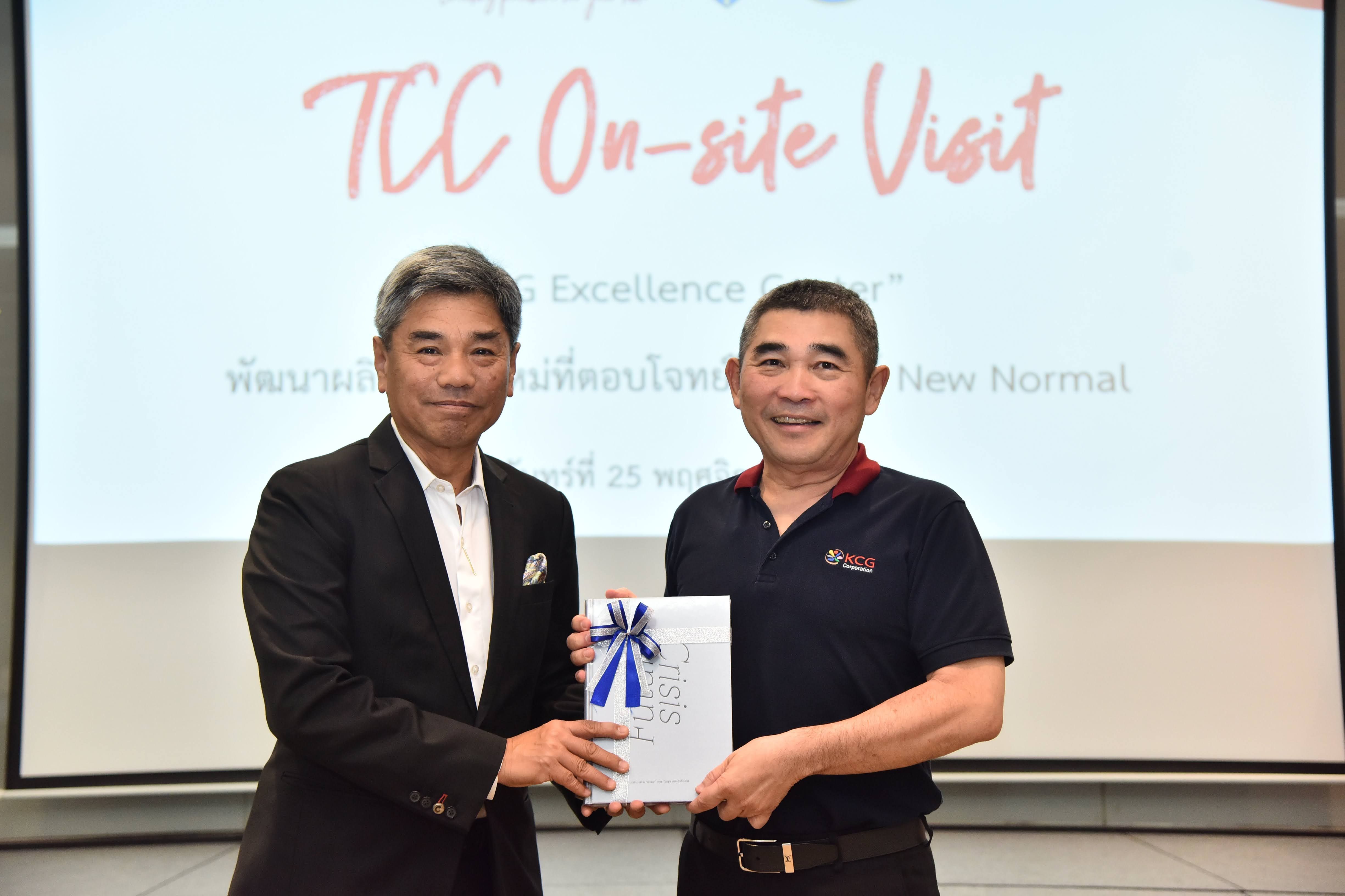 Two men in business attire exchanging a document during a TCC On-site Visit.