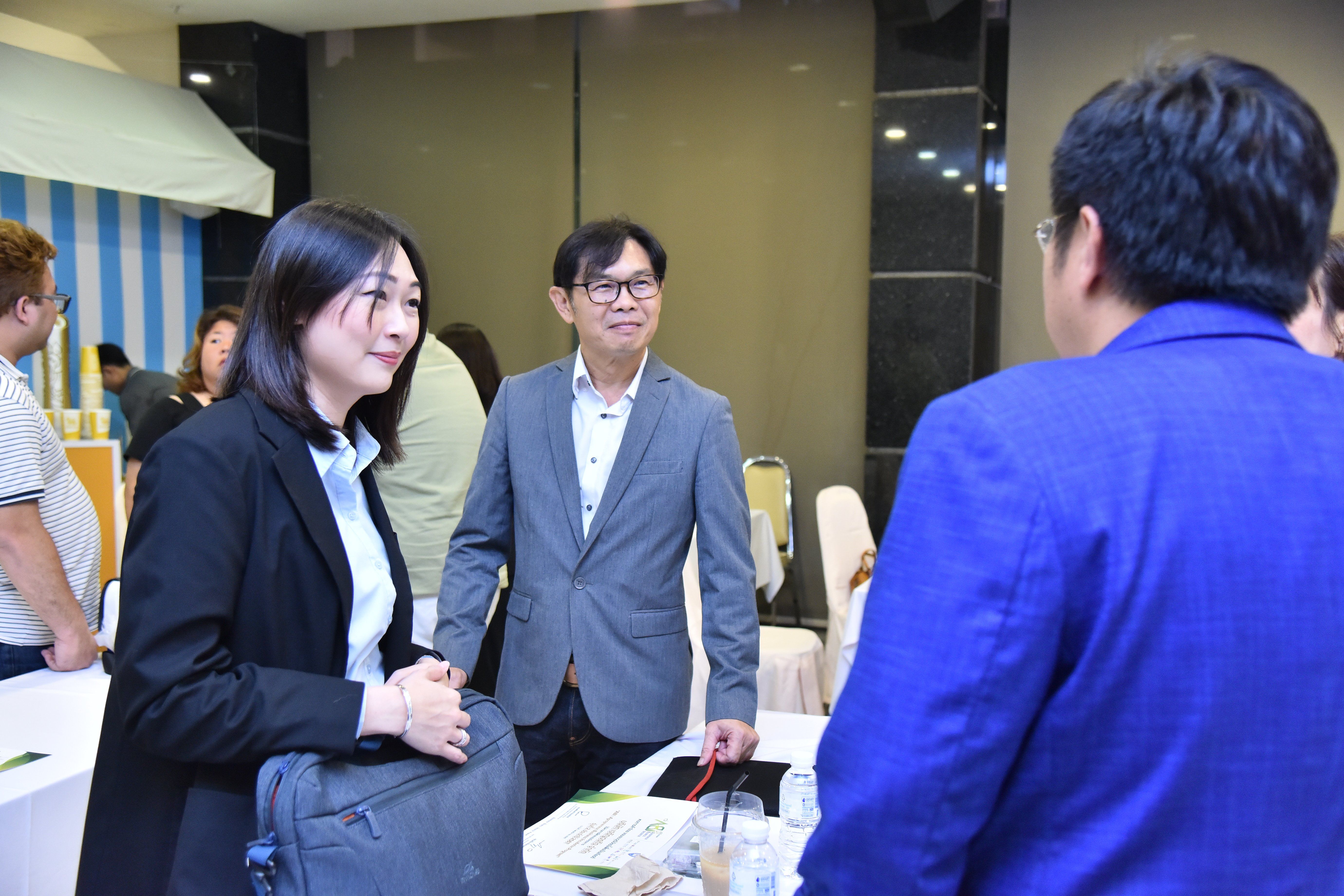Three professionals engaging in conversation at a busy networking event.