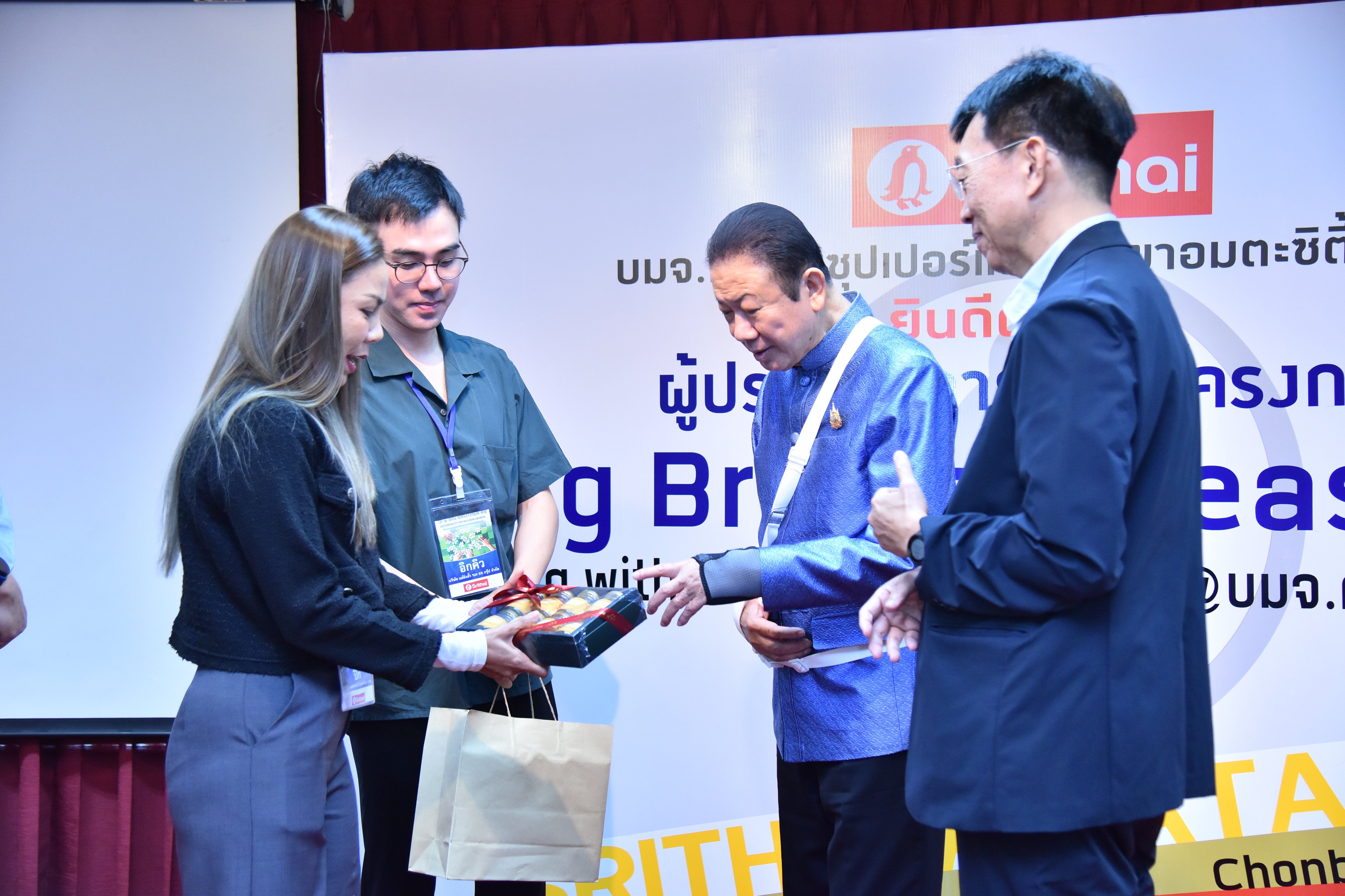 A woman presents an award to a man in a blue shirt at a corporate event.