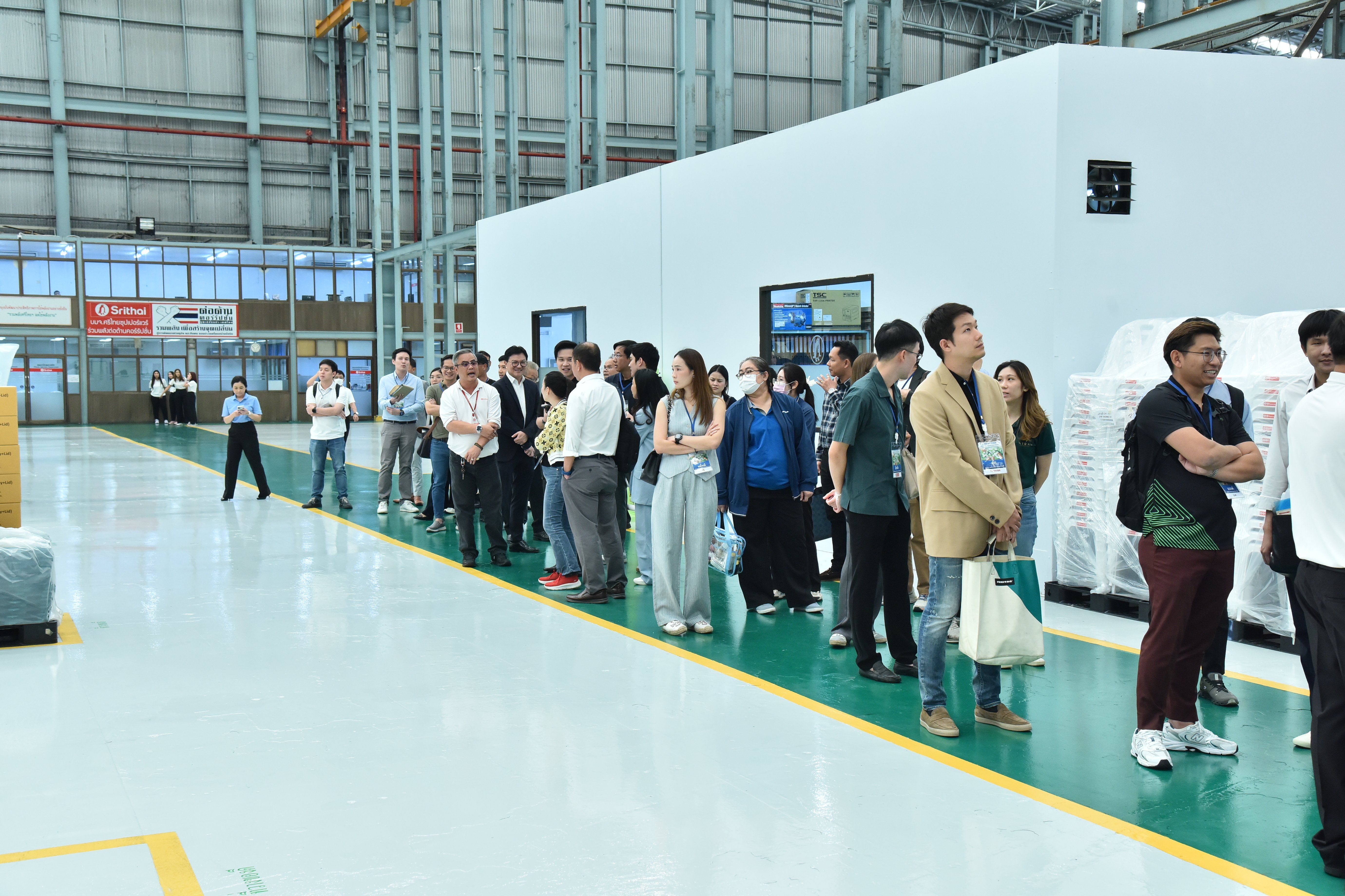 A group of people standing on a clean factory floor during a facility tour.