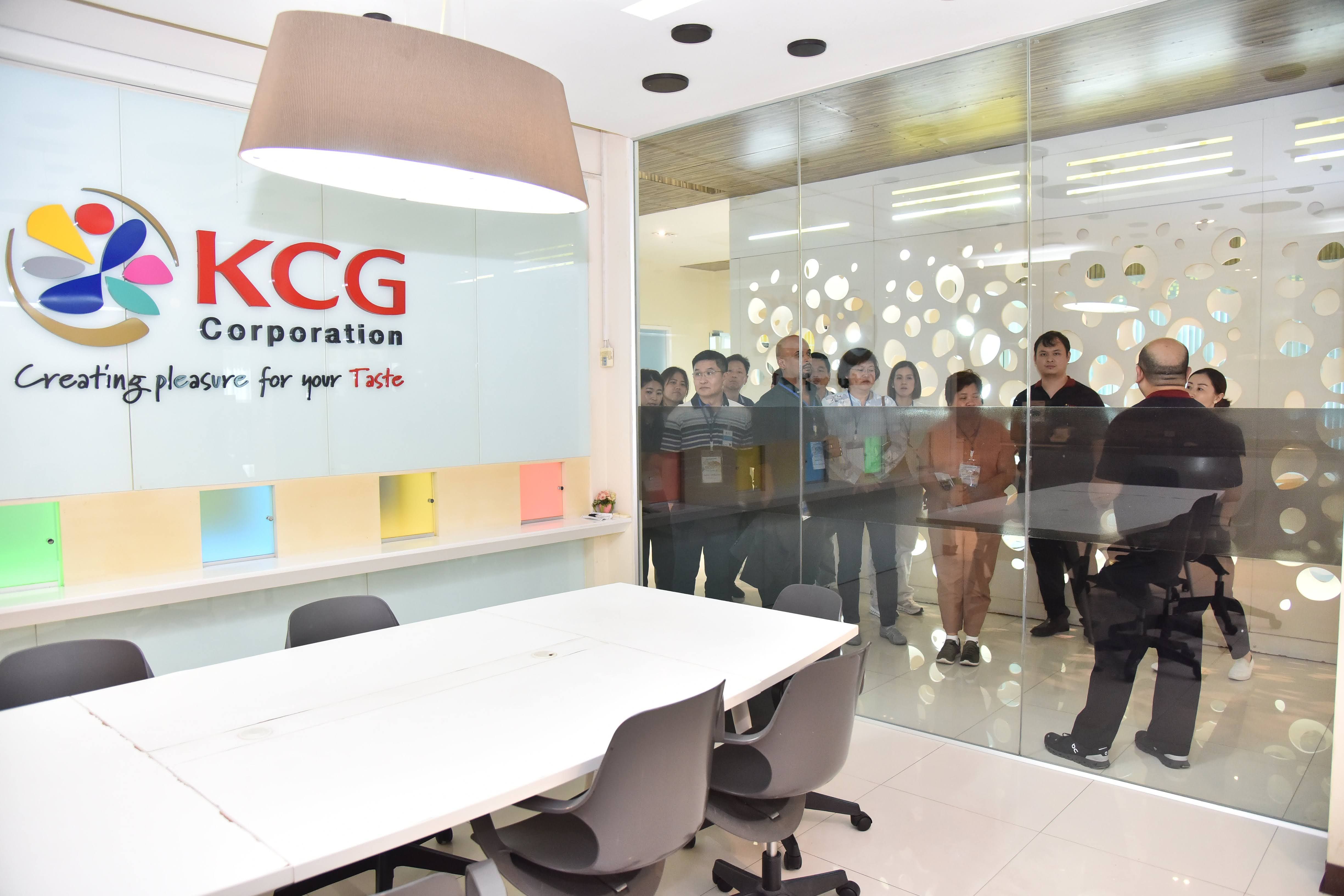 KCG Corporation office interior with conference table and people outside glass wall.