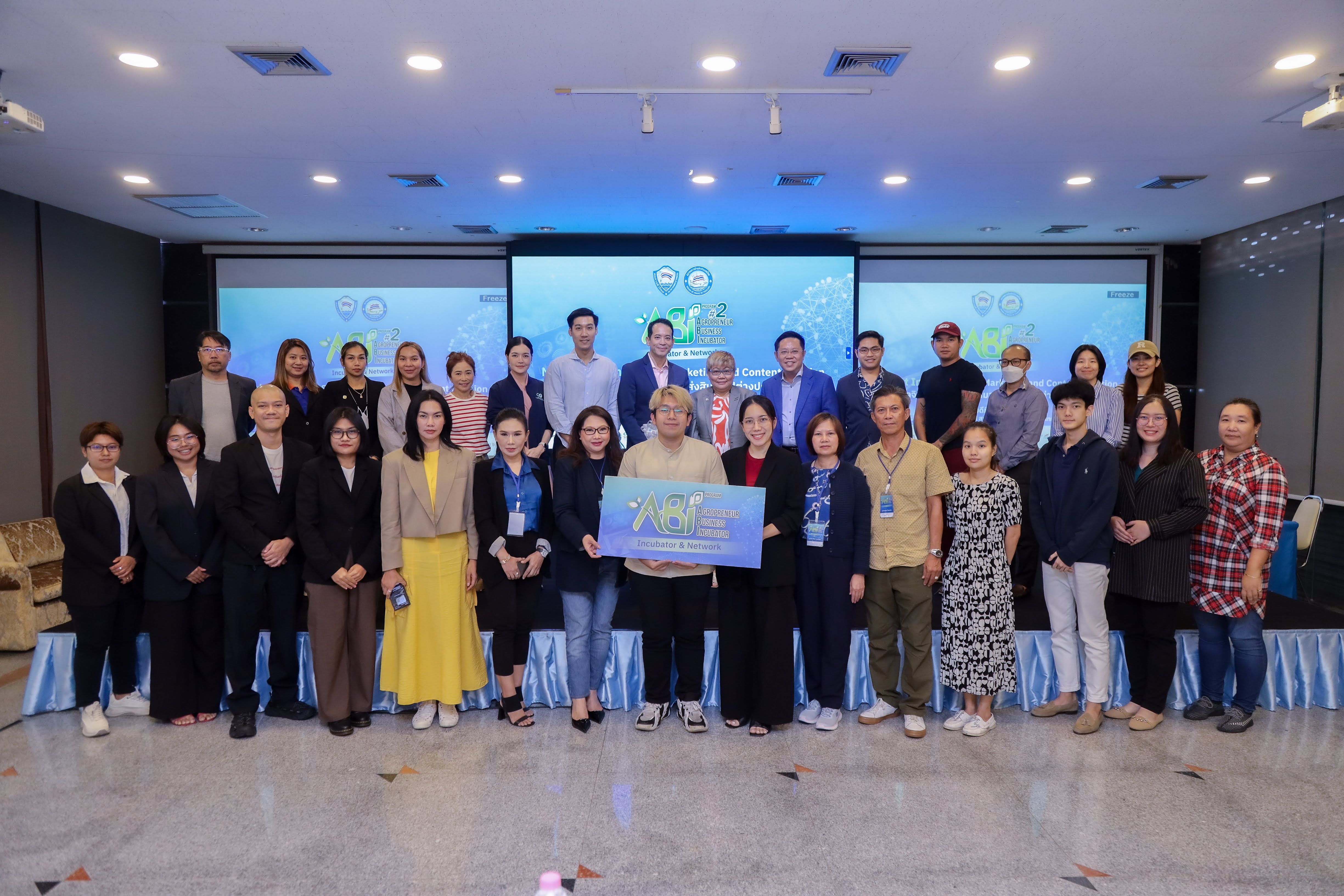 A large group of diverse professionals stands smiling, holding a certificate in a conference room.