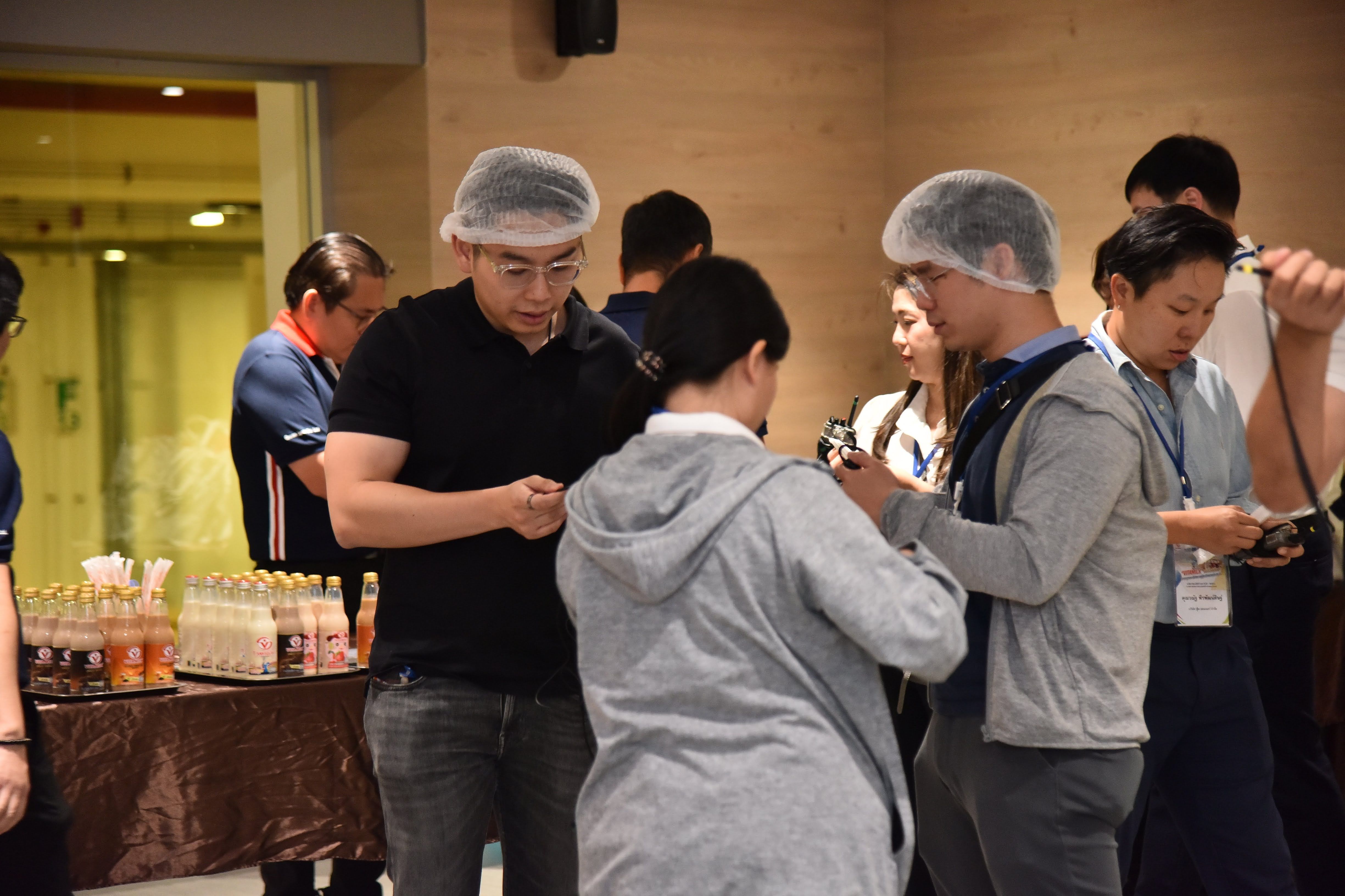 Group of people wearing hairnets gathered, engaged in an interactive activity.