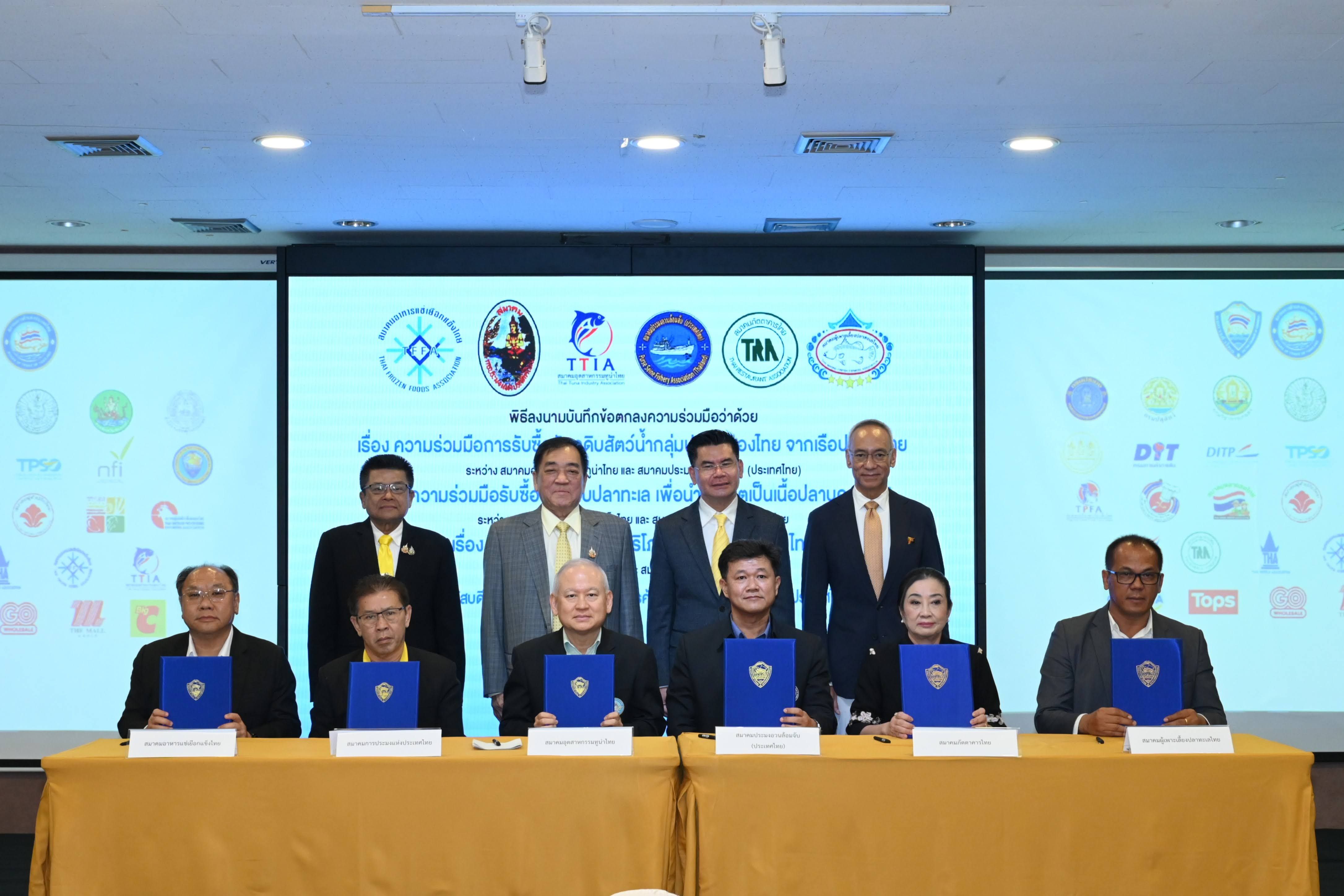 Nine men, five seated, four standing, at a formal document signing ceremony.