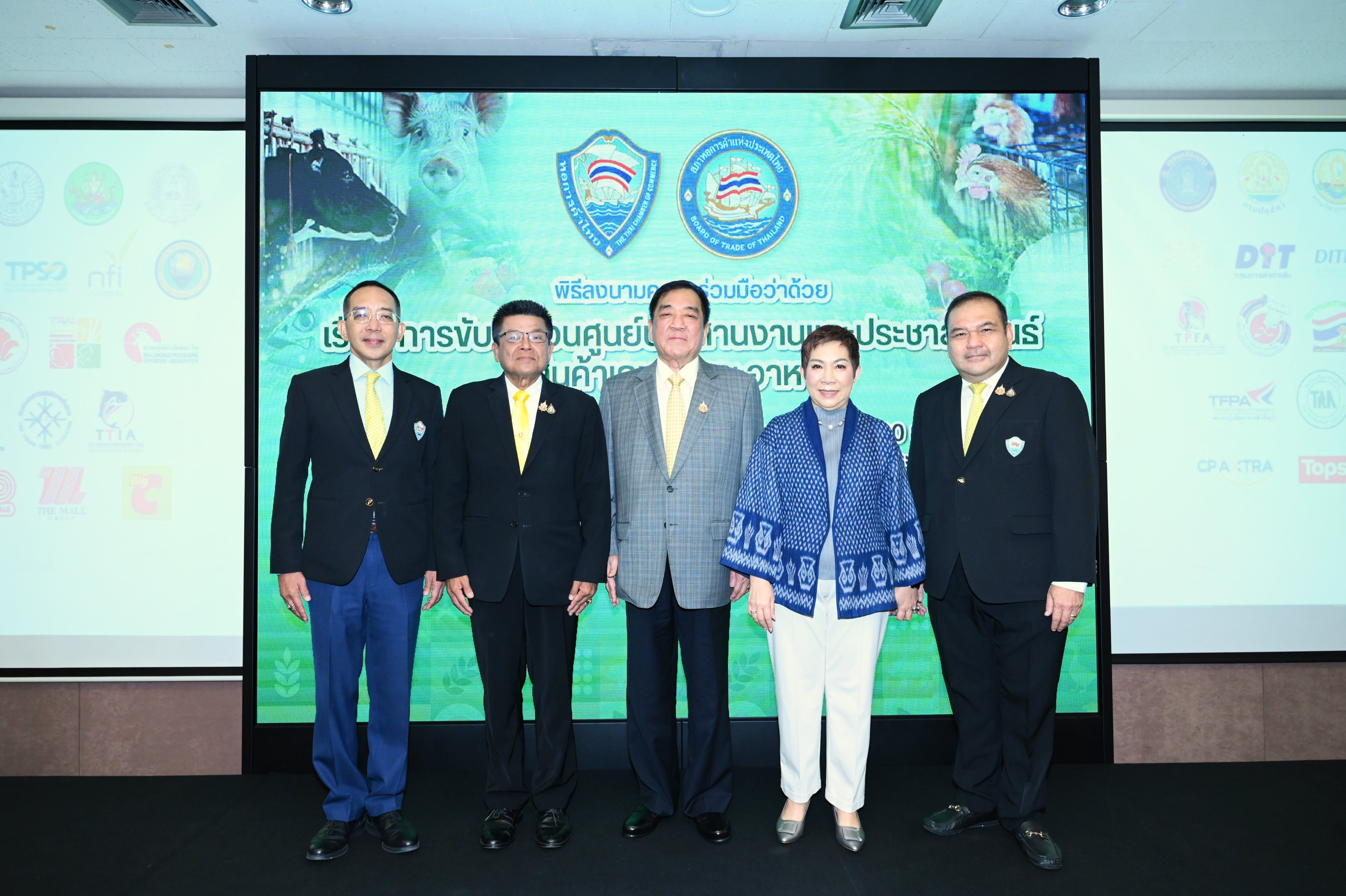 Five professionals, four men and one woman, stand formally before a large screen presentation.