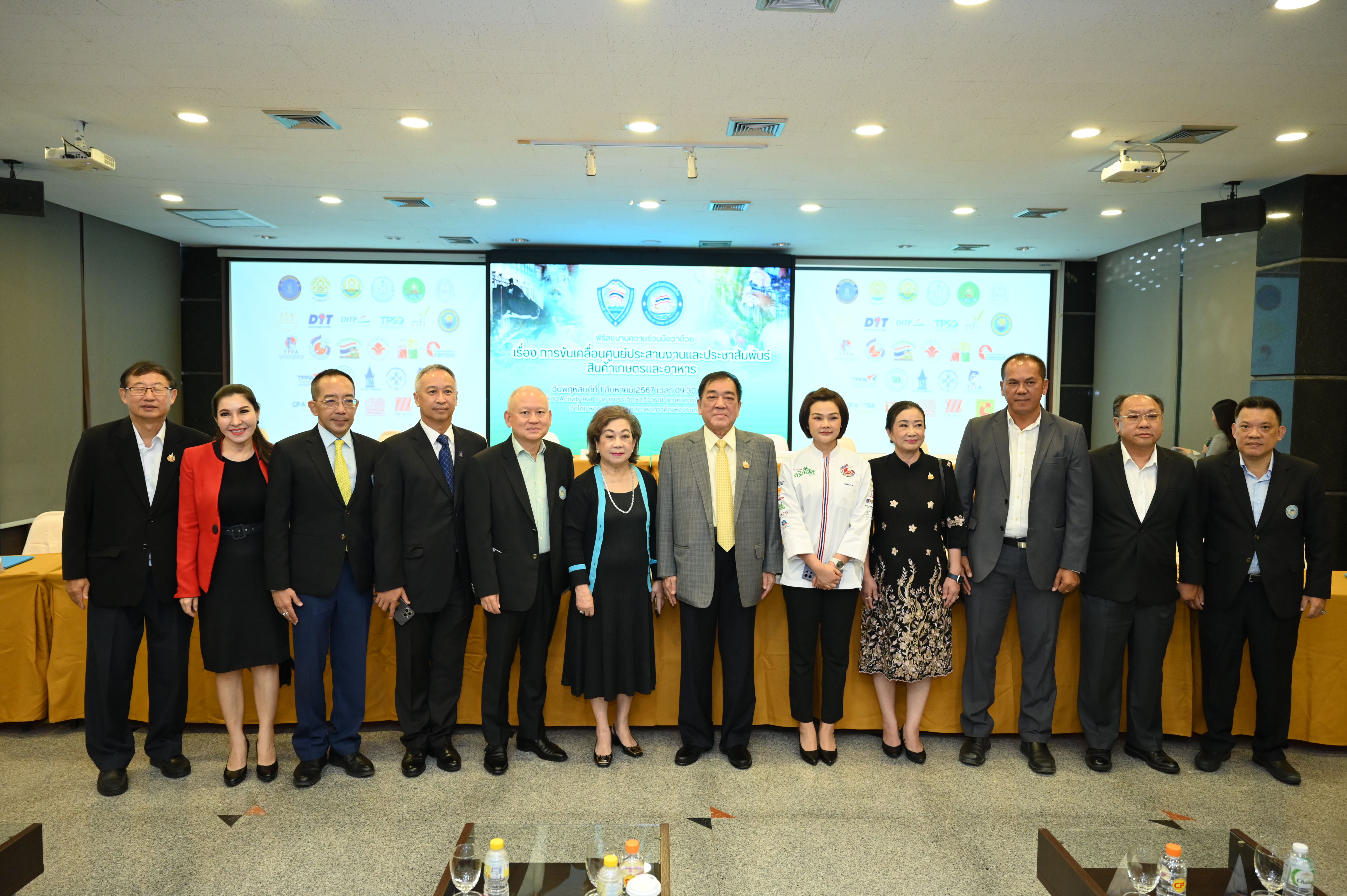 A group of 12 professionals stands formally in a conference room with a presentation screen.