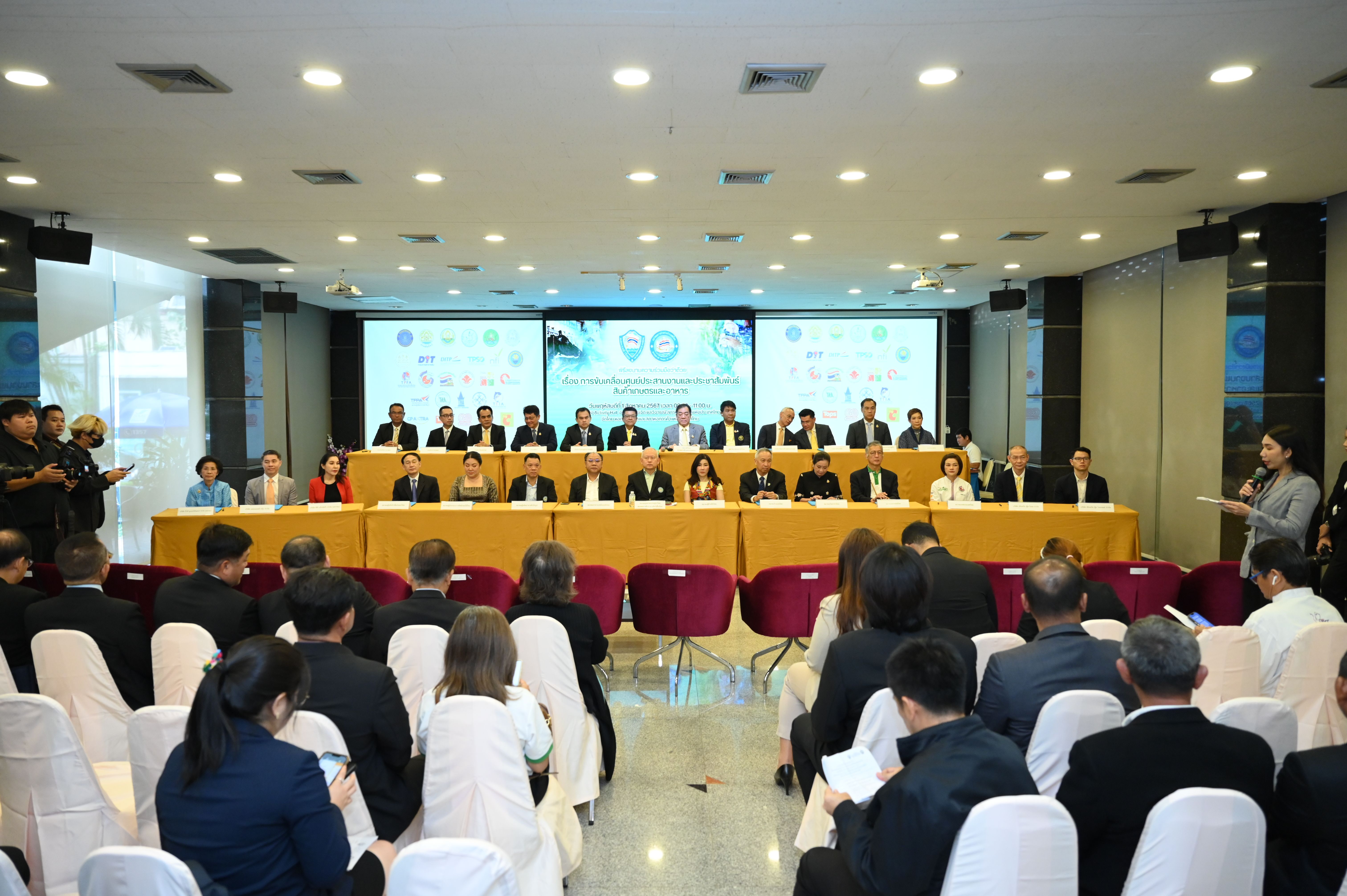 Professionals attend a conference with a long panel table and audience in a modern room.
