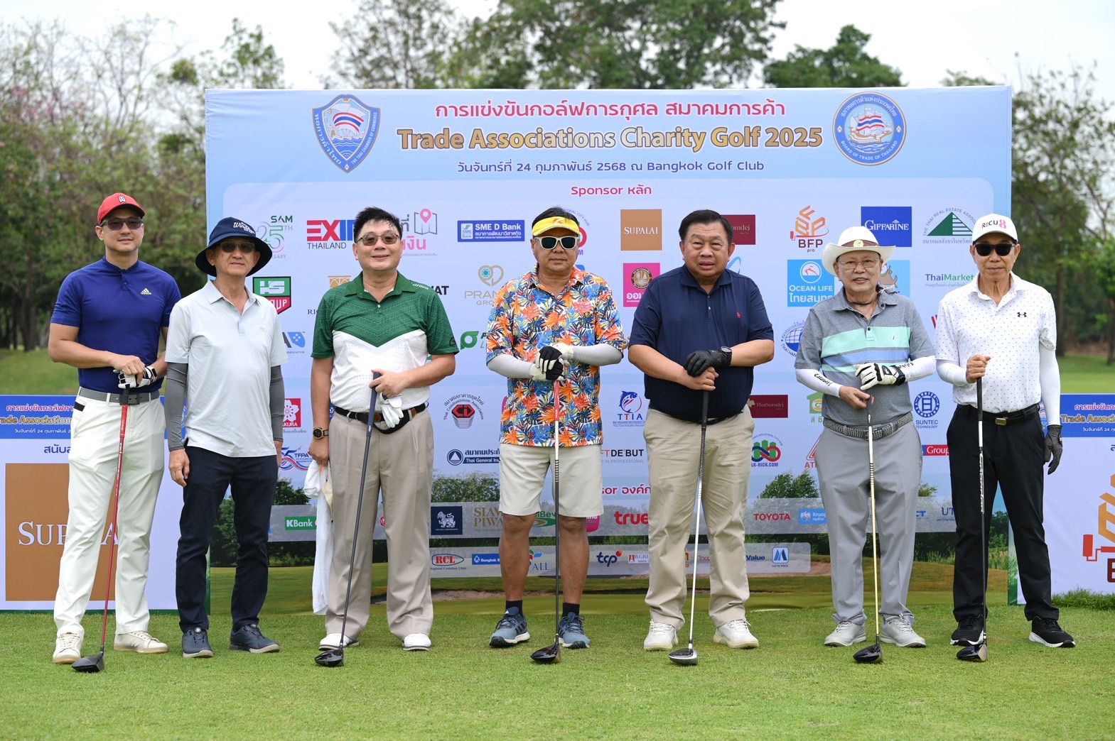 Seven men in golf attire stand on a course before a 'Charity Golf 2023' banner.