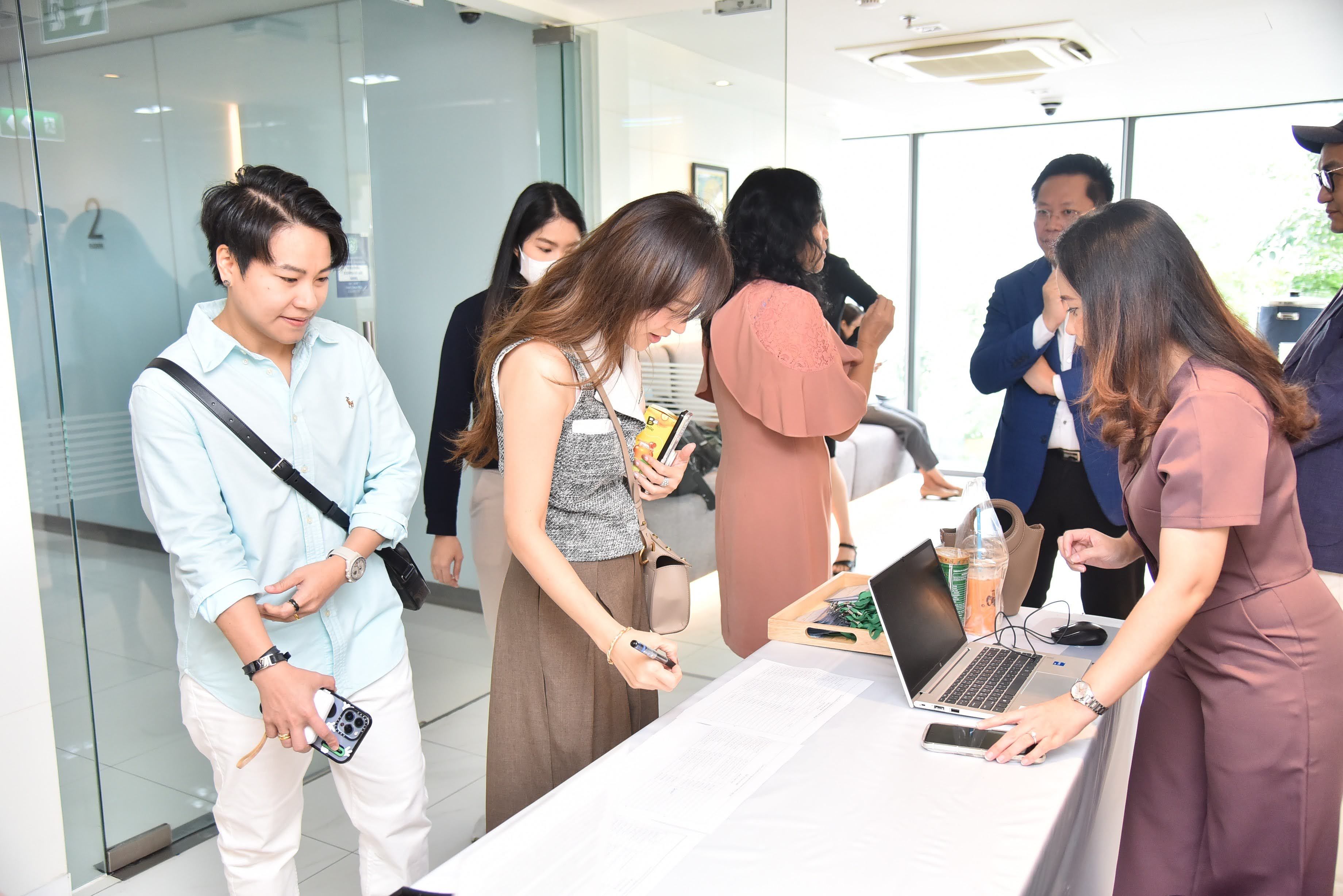 People checking in at a registration table with a laptop in a modern event space.