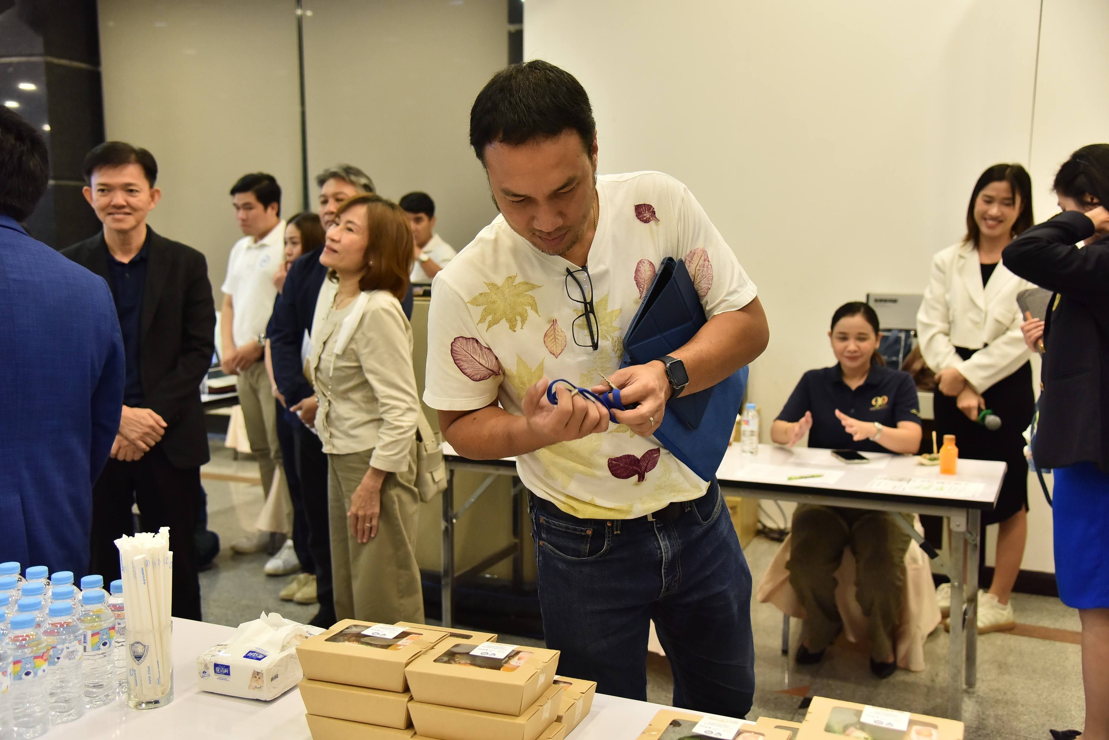 Man in patterned shirt examining small items on a table at an event.