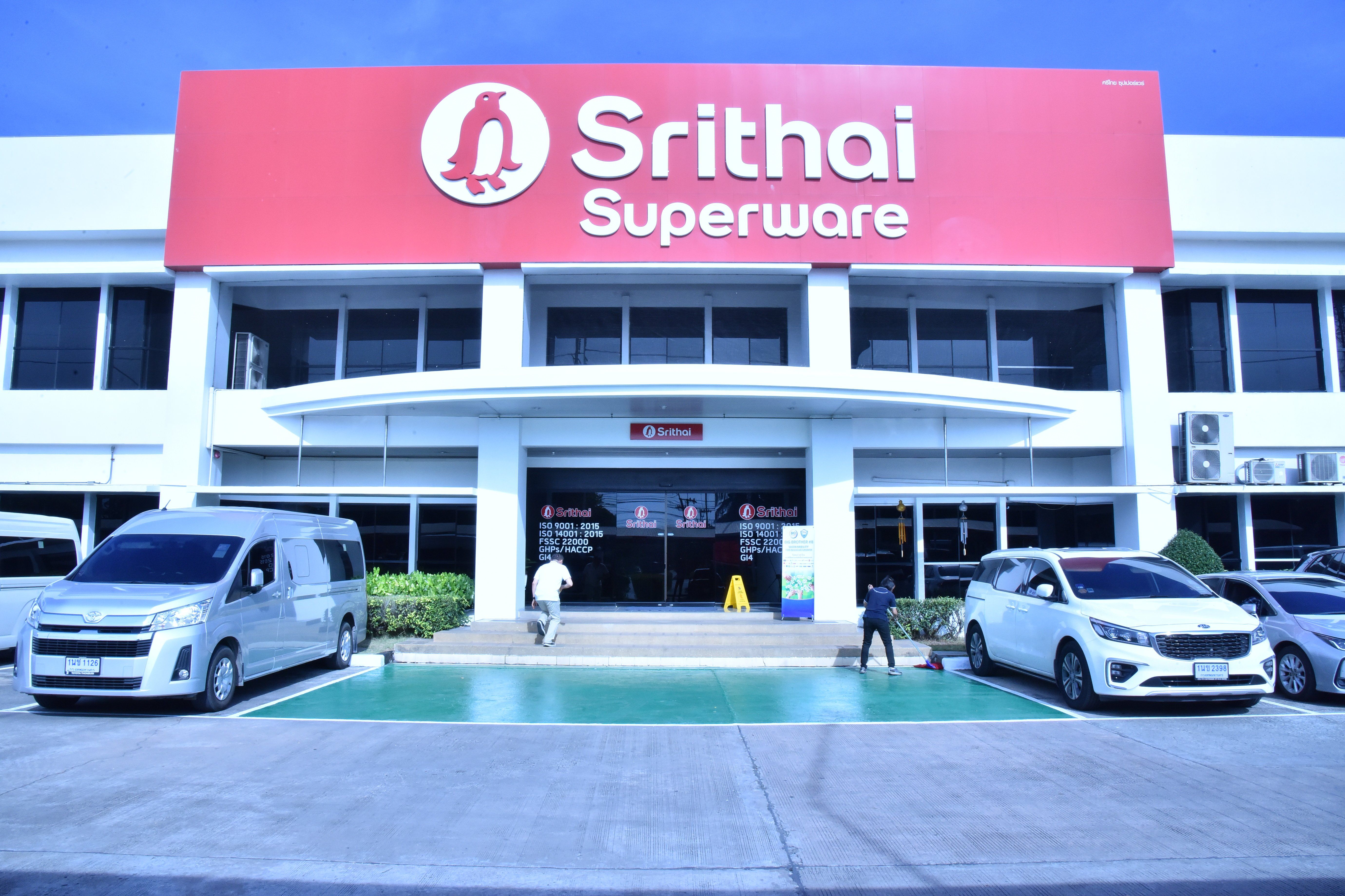Exterior view of the Srithai Superware building featuring its prominent red sign and parked cars.