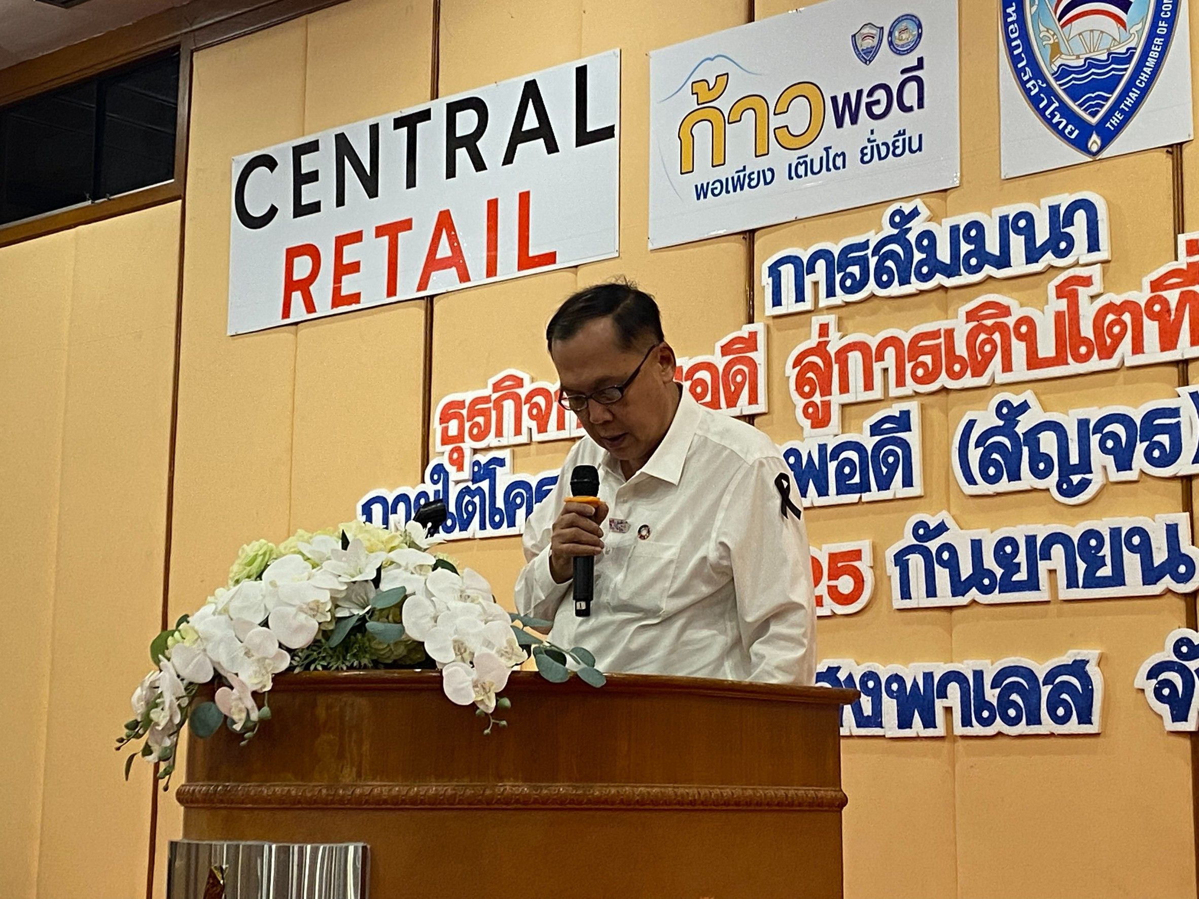 Man speaking at a seminar podium with a Central Retail banner and Thai text.