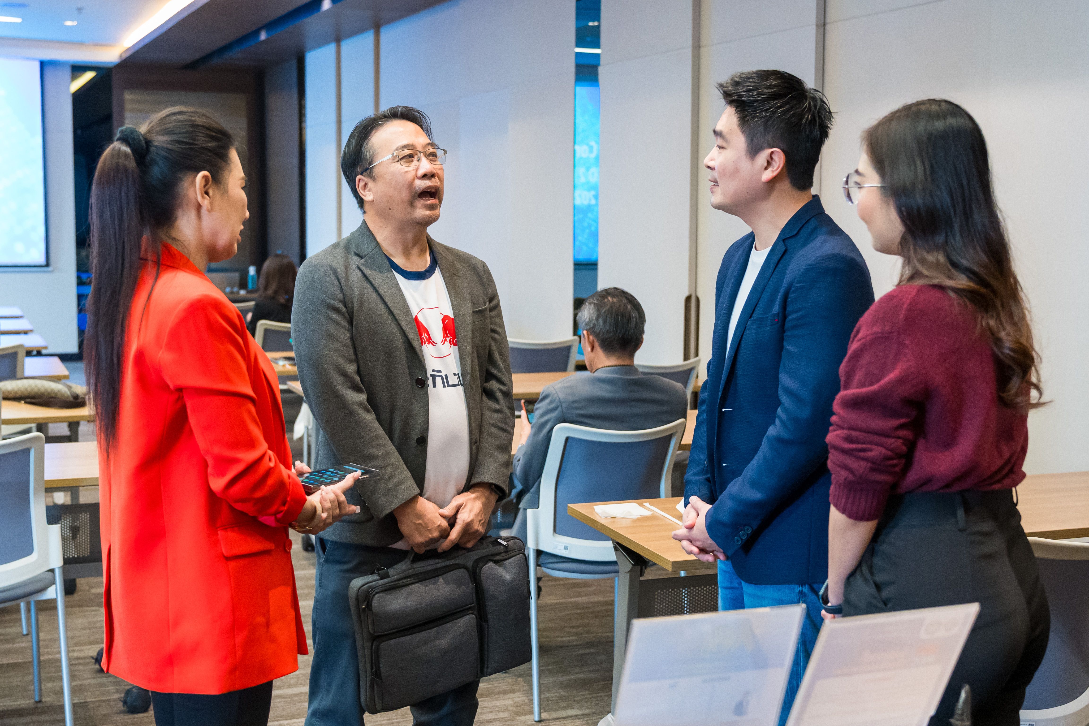 Four professionals engaged in conversation during a meeting break in a modern conference room.