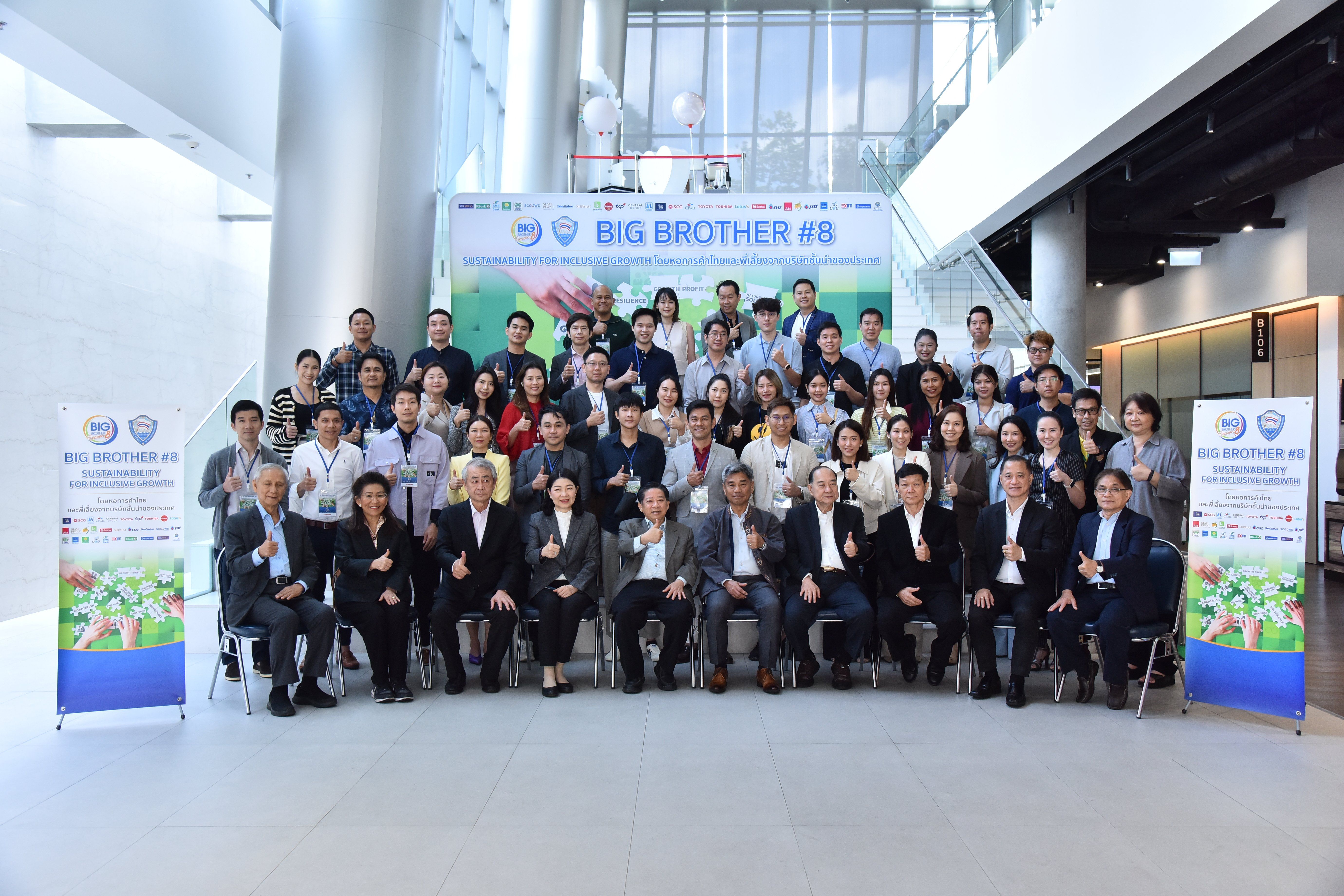 Large group of people, standing and seated, in front of "BIG BROTHER #8" banner.