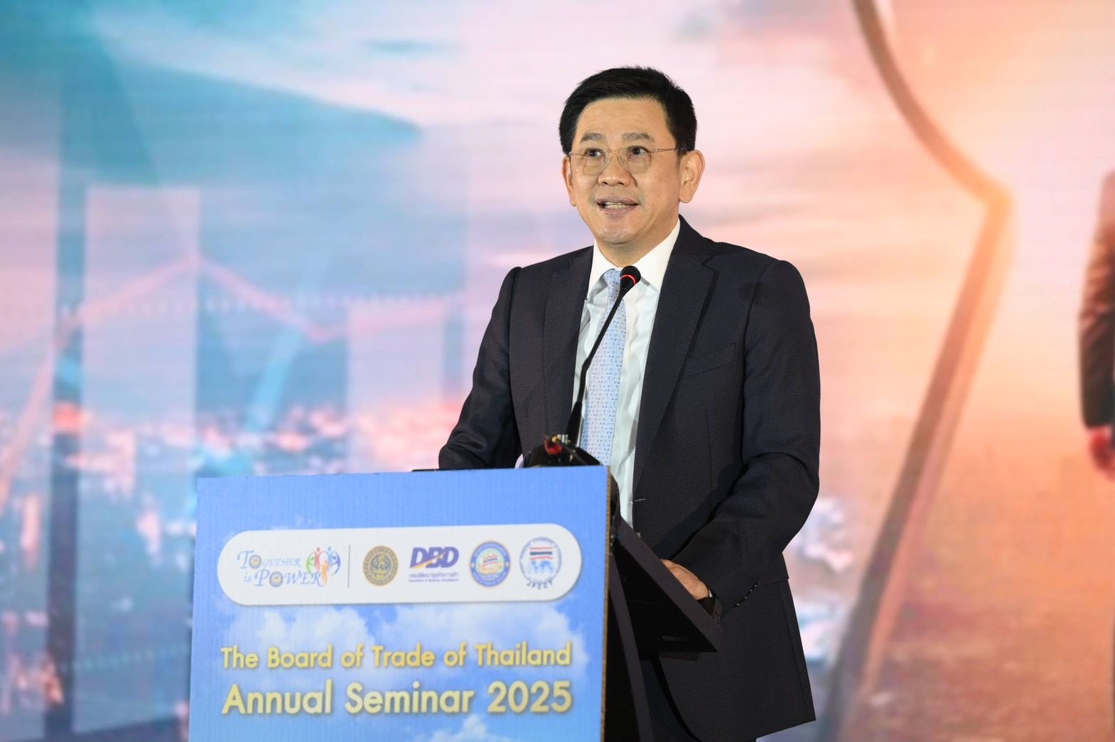 Man in suit speaks at podium during 'Annual Seminar 2025' on healthcare.
