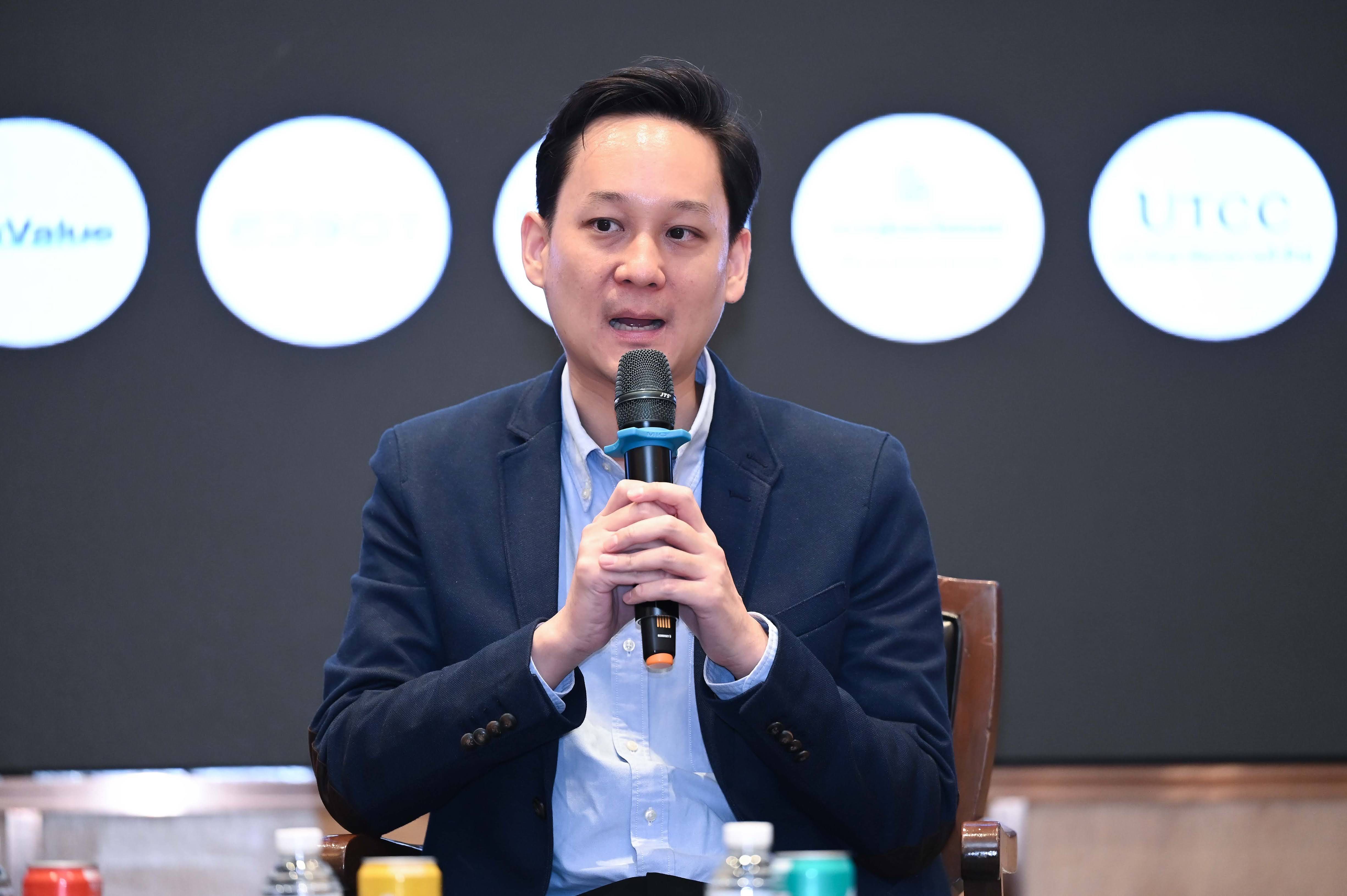 Man in a blue suit speaking into a microphone at a professional conference.