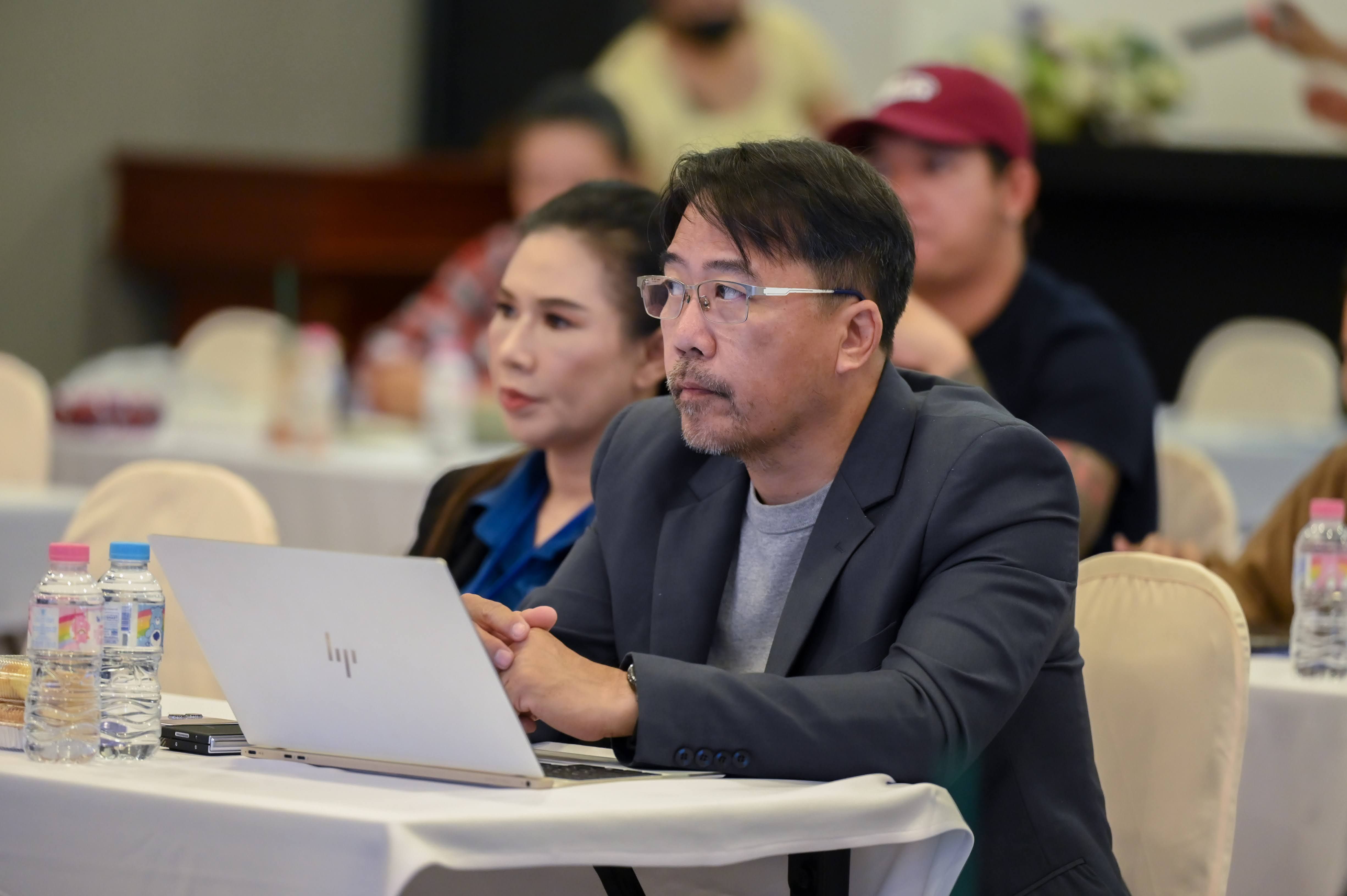 Focused man in glasses at a conference table with a laptop.