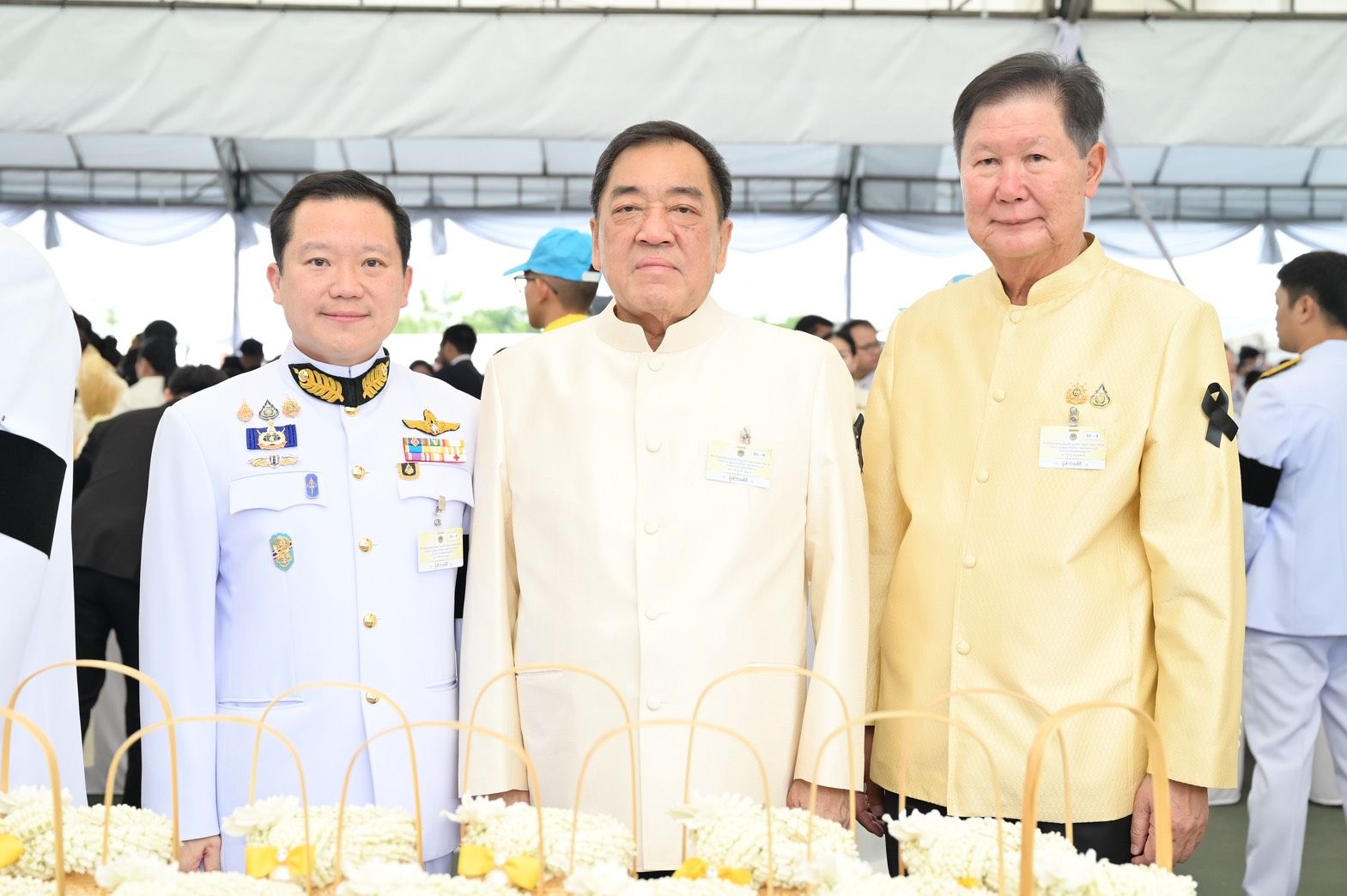 Three men, two in traditional formal attire and one in a white military uniform.