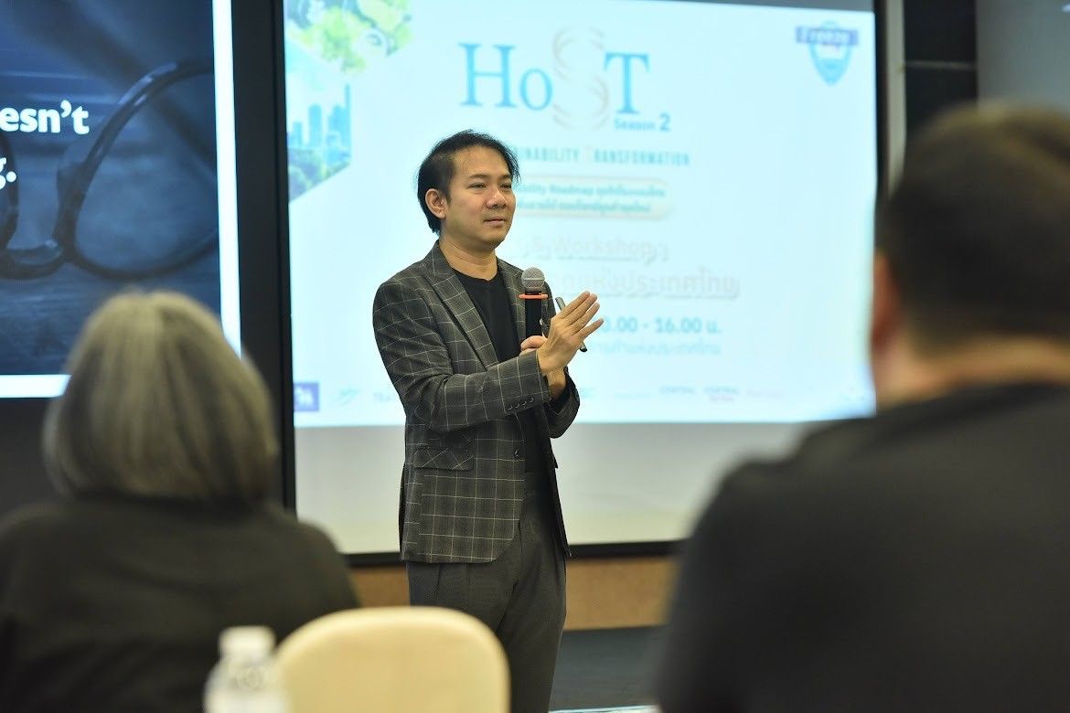 Man in patterned suit speaks and gestures before a screen to an audience.