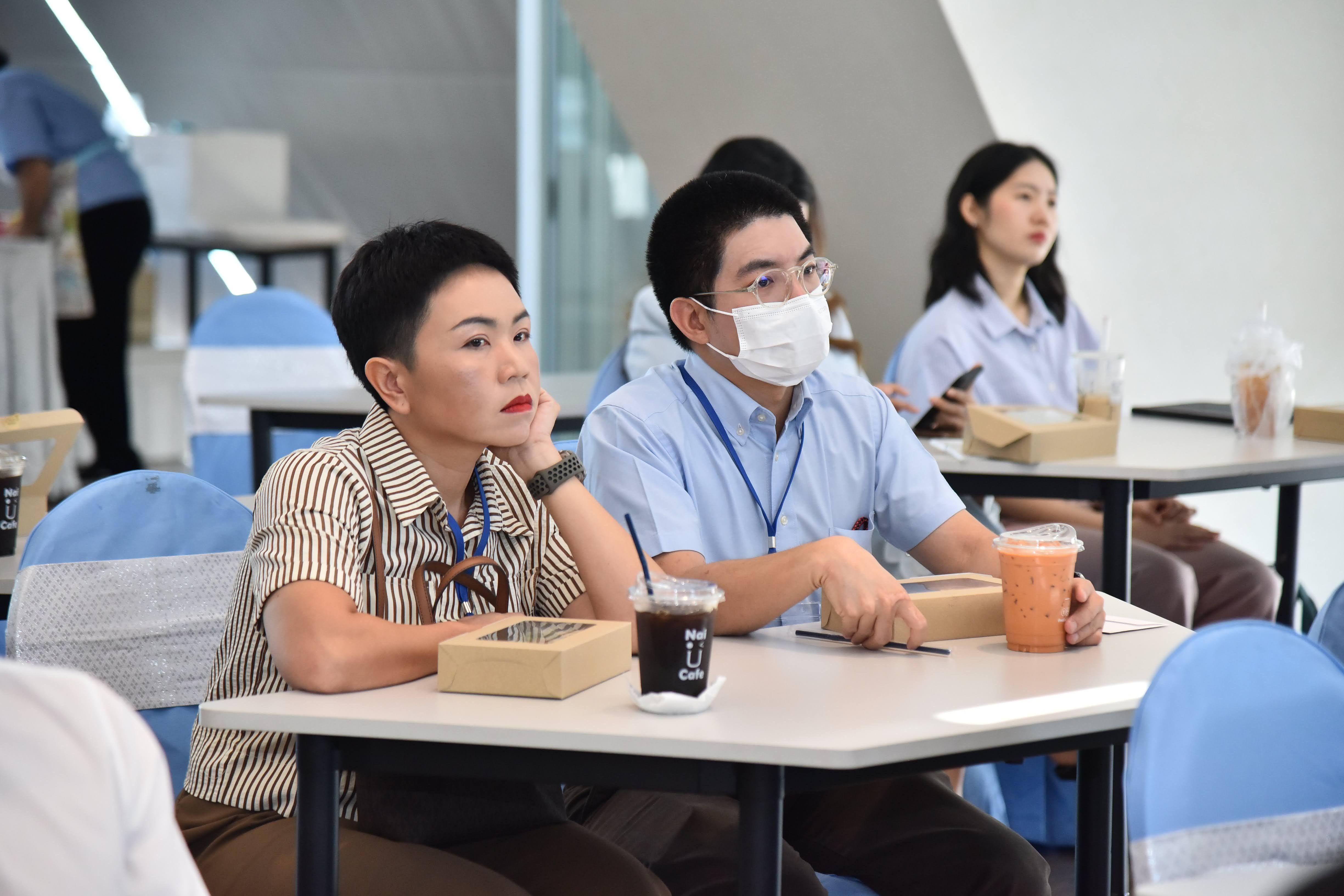 Two attentive individuals, a woman and a man in a face mask, seated at a table.